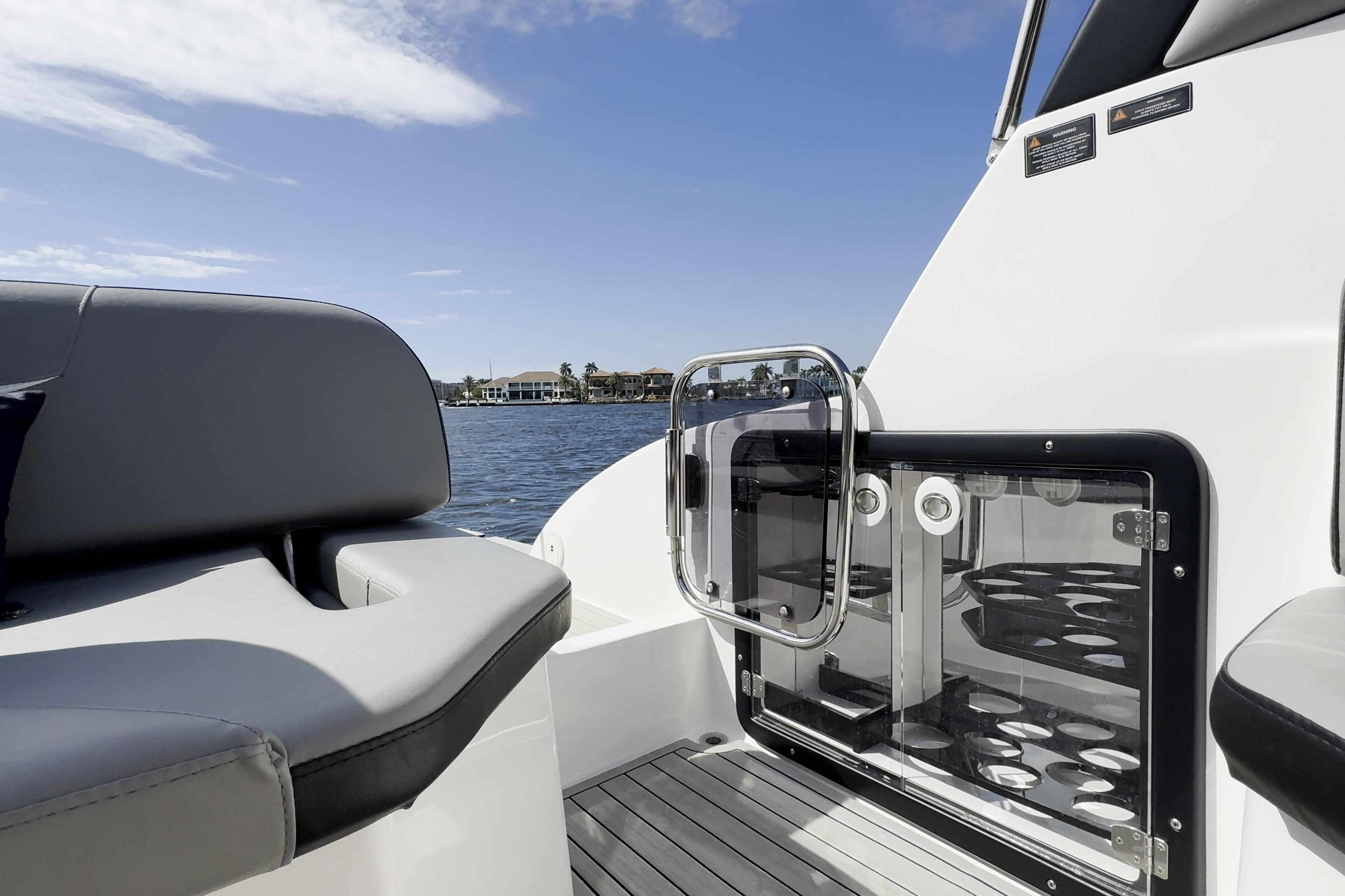 Luxury seating and glass door on 2027 Hanover 305 boat, with scenic waterfront view.