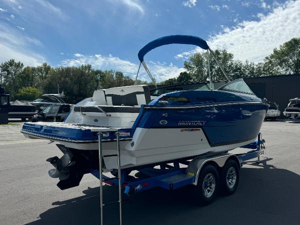2018 Monterey 258 Super Sport boat on trailer, blue and white, parked outdoors.