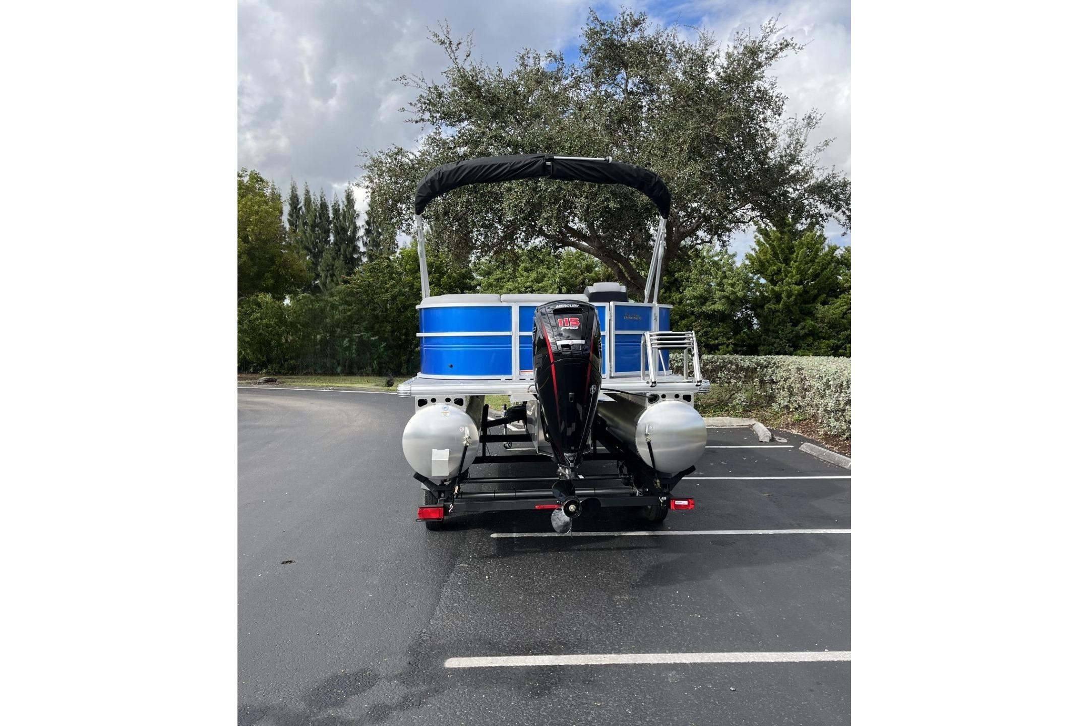 2026 Sun Tracker Party Barge 20 DLX pontoon boat in parking lot, rear view.