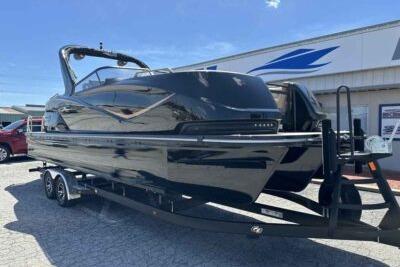 2025 SunCatcher Amara boat on trailer, sleek black design, parked outdoors under clear sky.