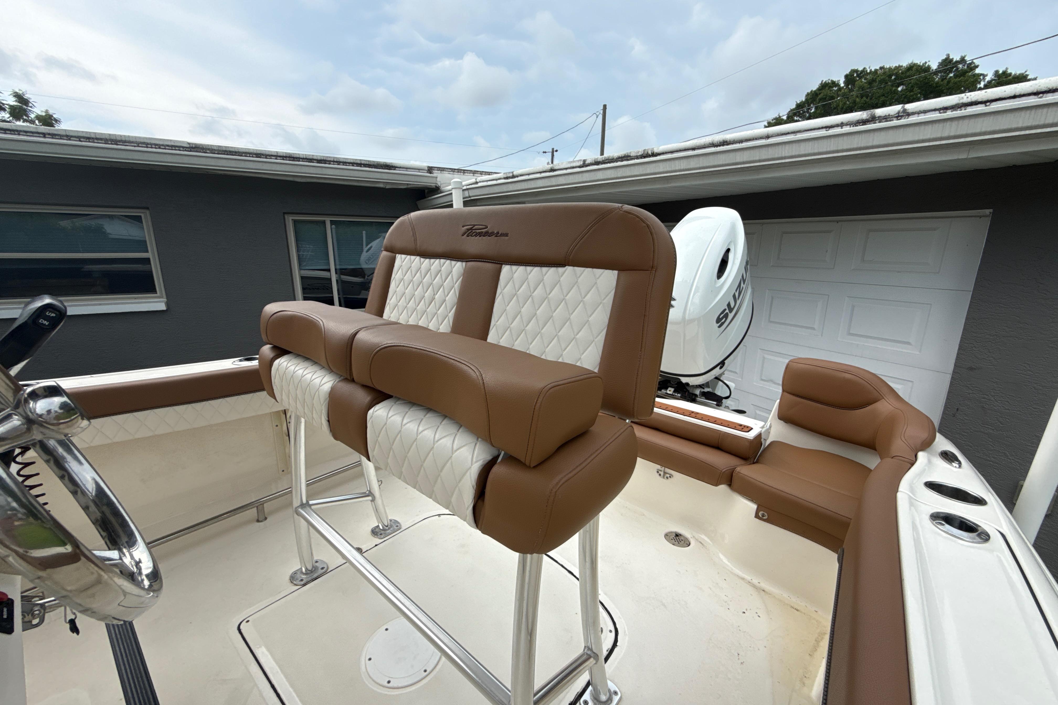2023 Pioneer 202 Islander boat with brown and white seating, parked near a garage.