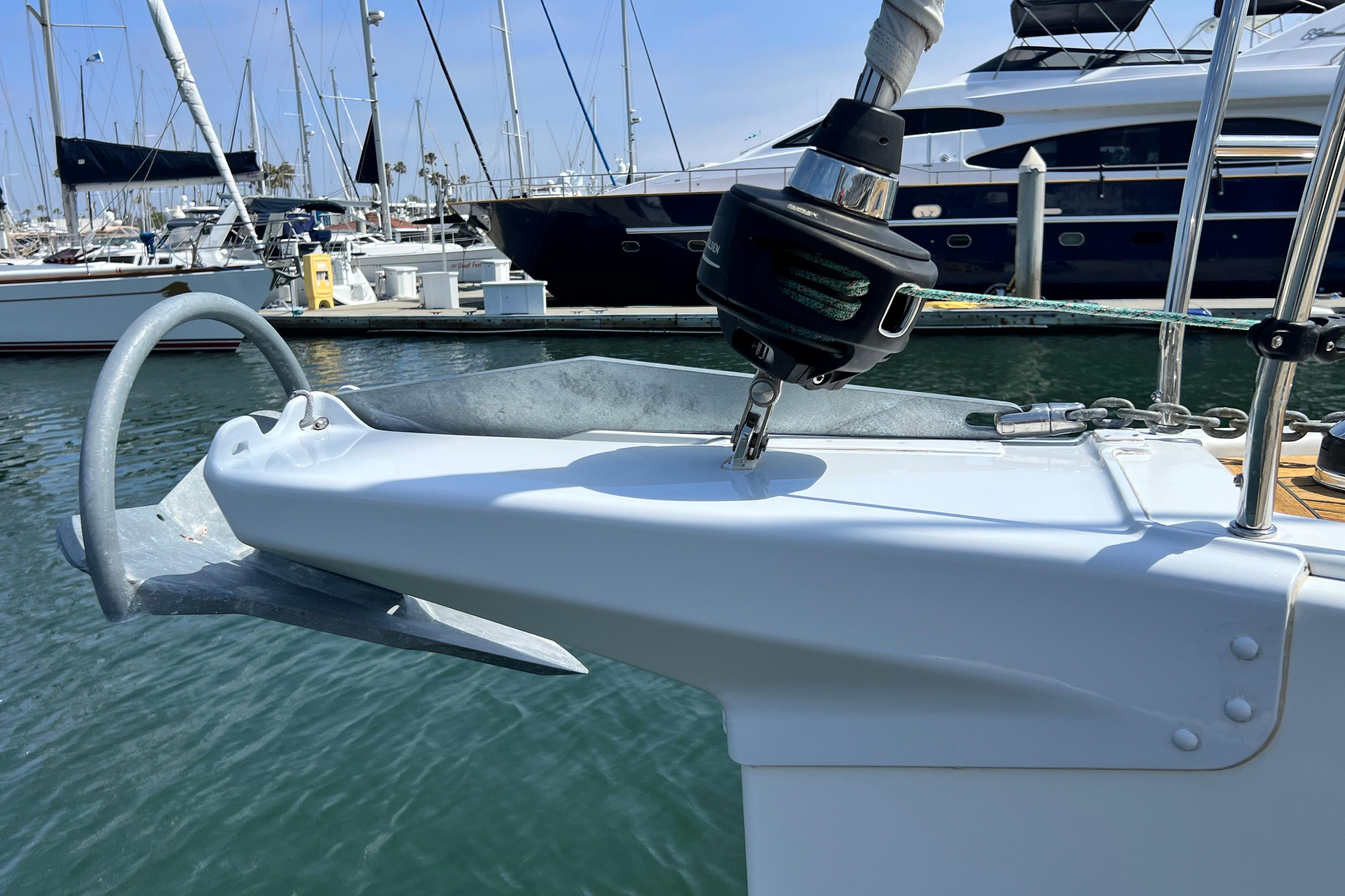 Bow of a 2016 Hanse 455 yacht with anchor and marina background.