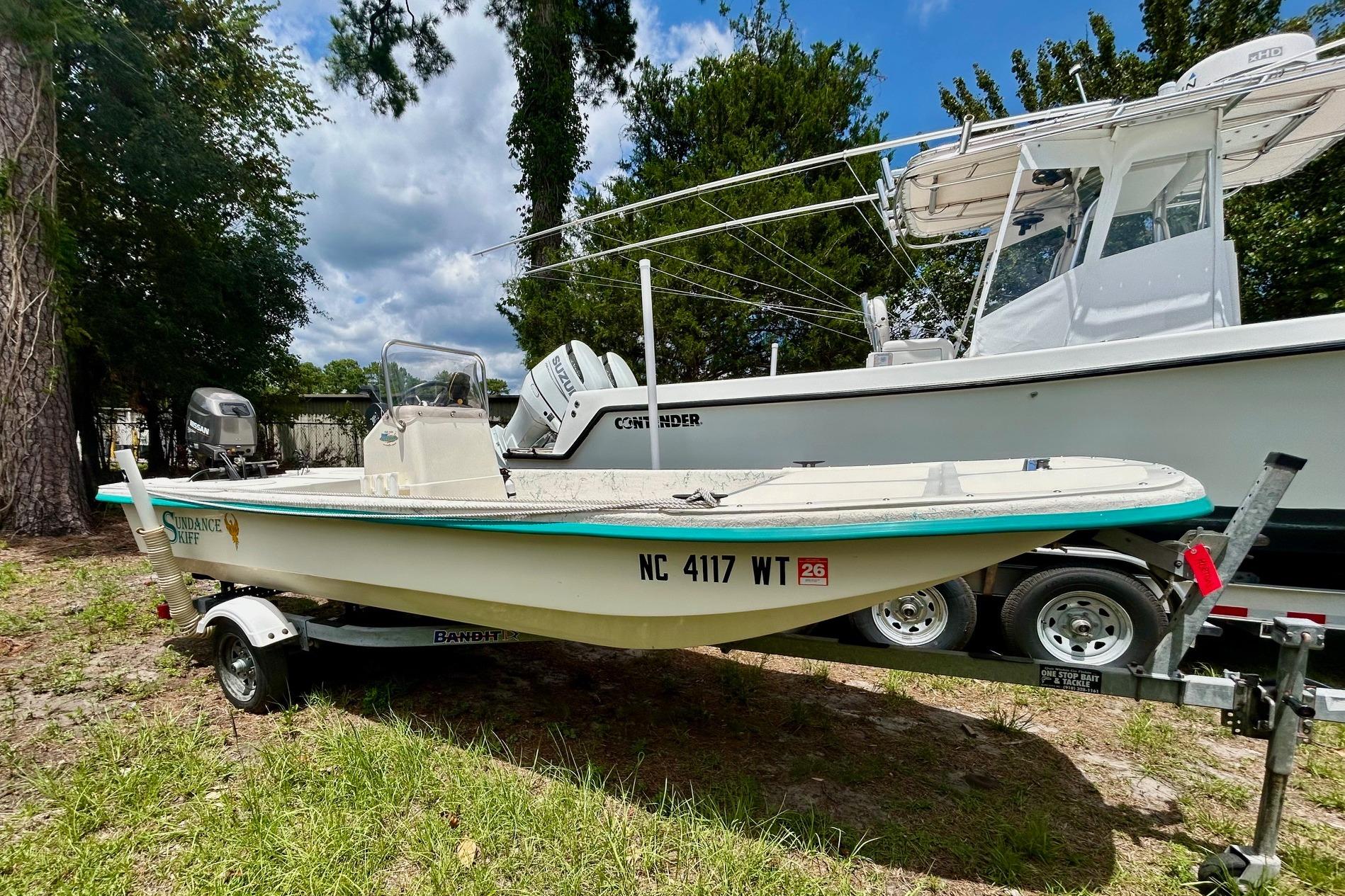 2002 Sundance K16CC boat on trailer, parked outdoors with trees in background.