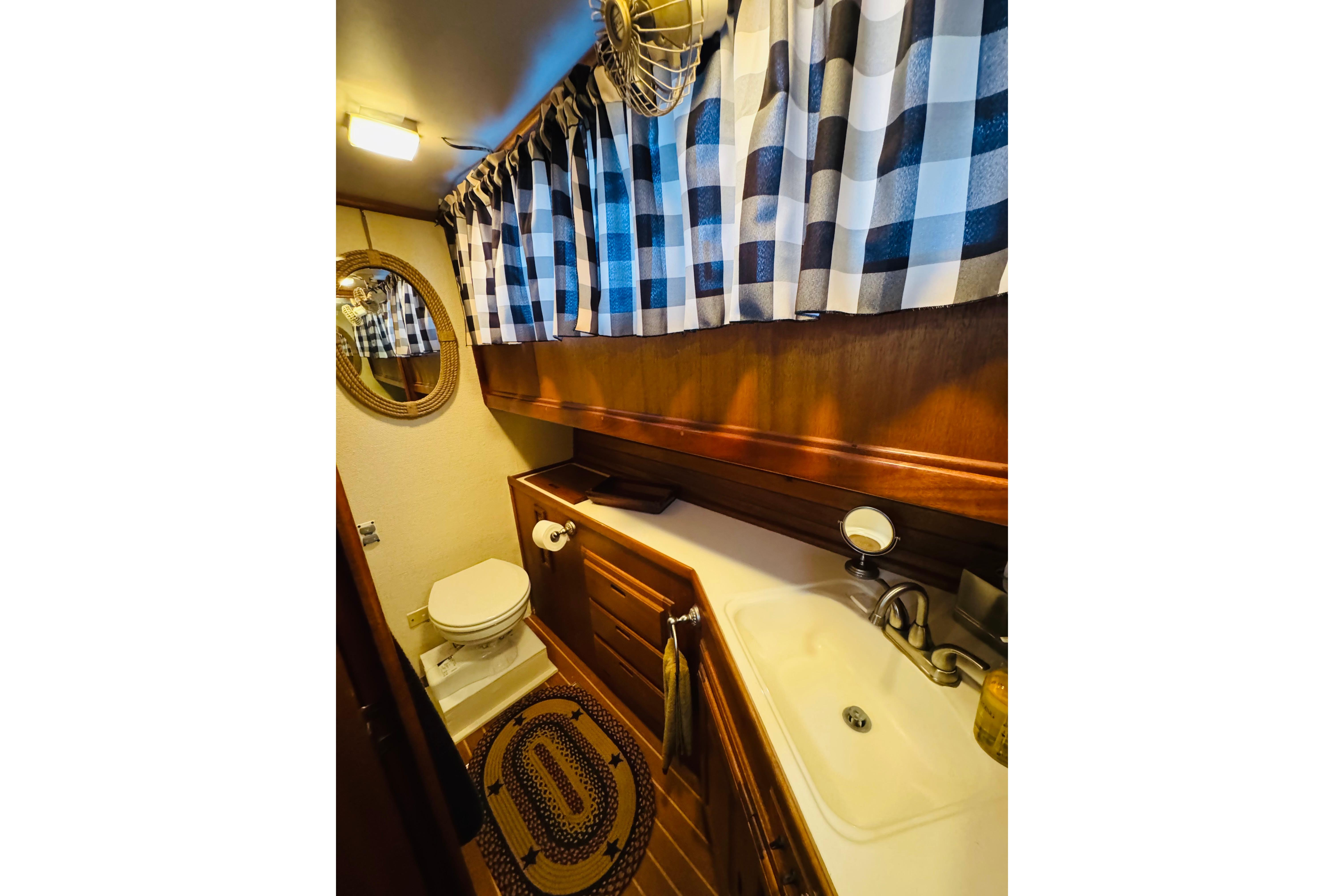 1978 Californian 42 LRC yacht bathroom with checkered curtains and wooden cabinetry.