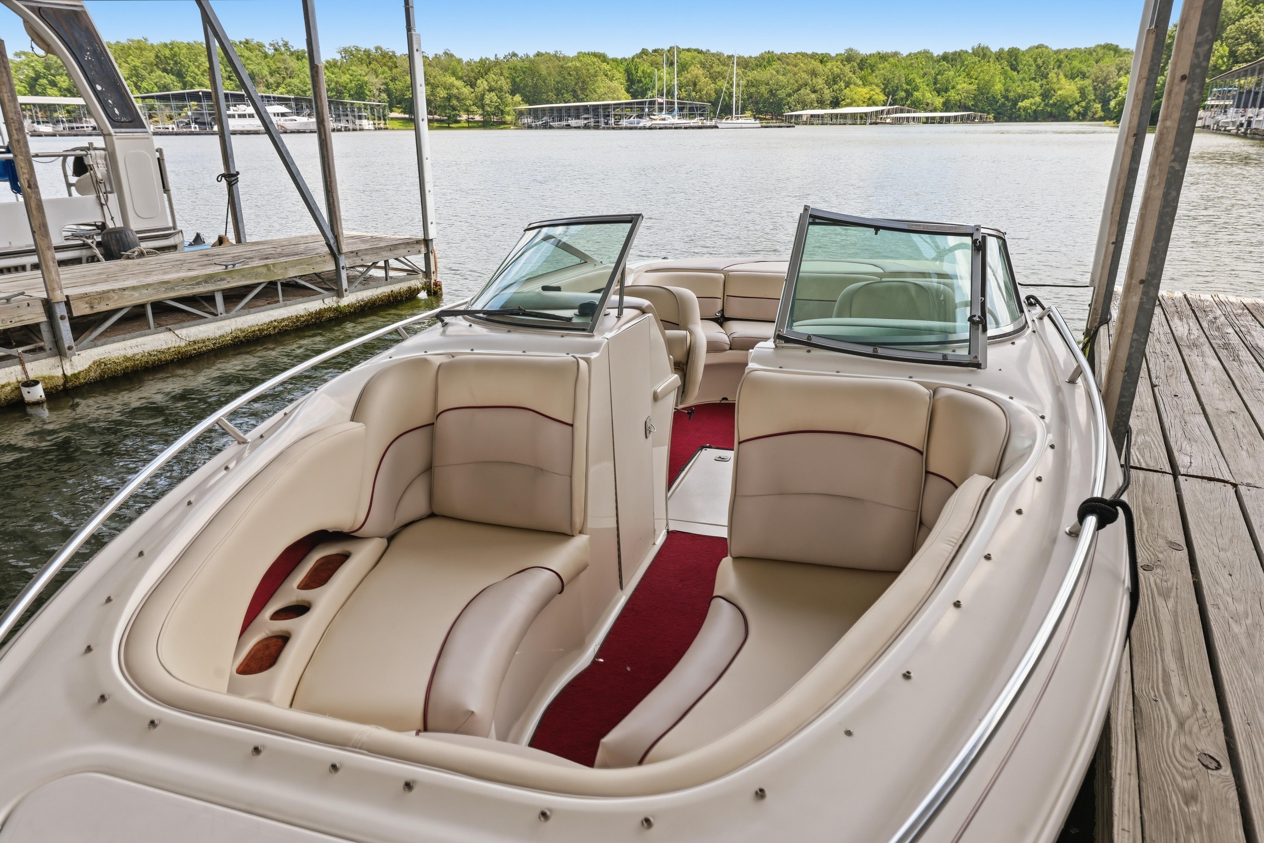 1997 Sea Ray 230 Signature boat with beige seating, docked by a serene lake.