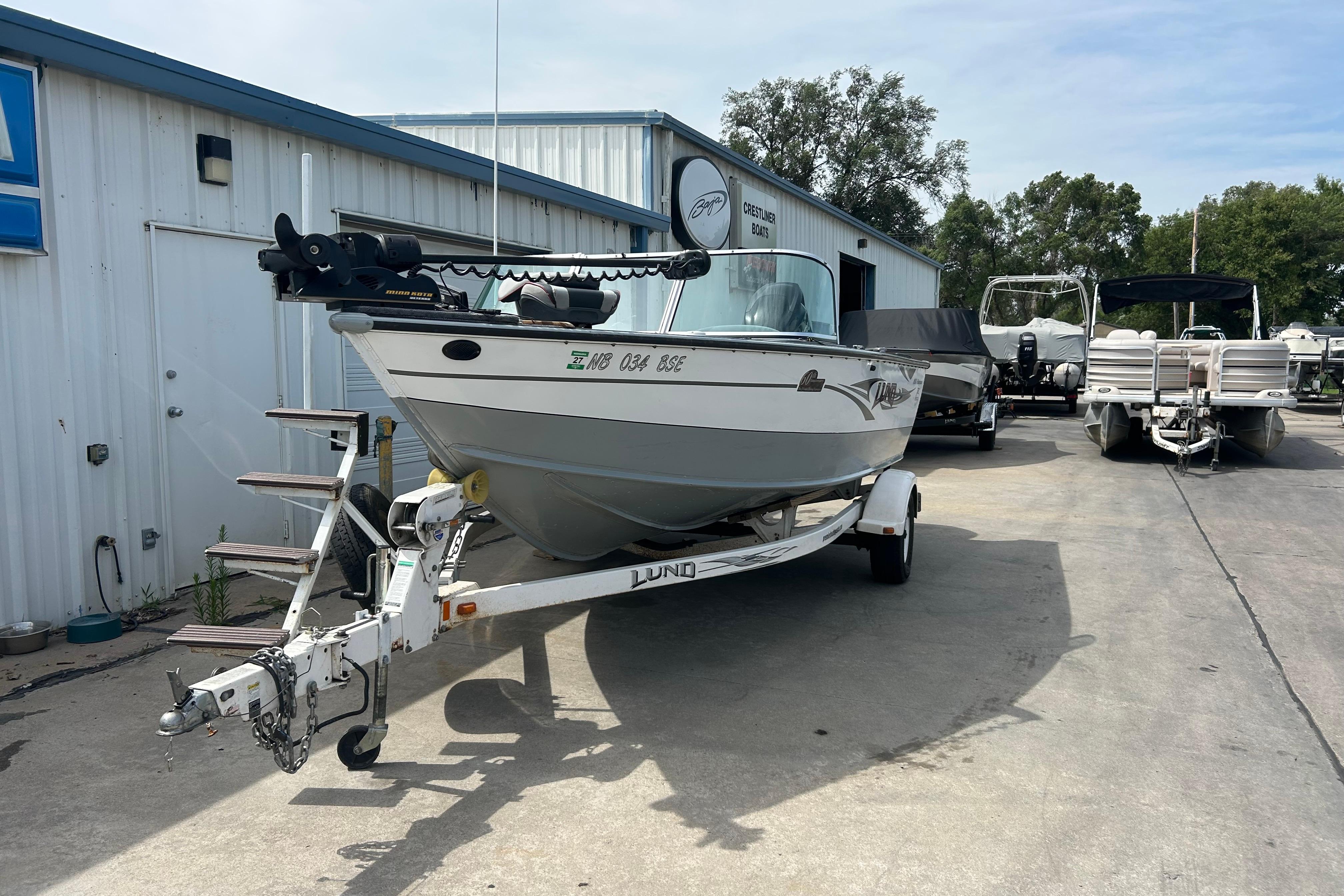 2008 Lund 1850 Fisherman boat on trailer outside a marine dealership.