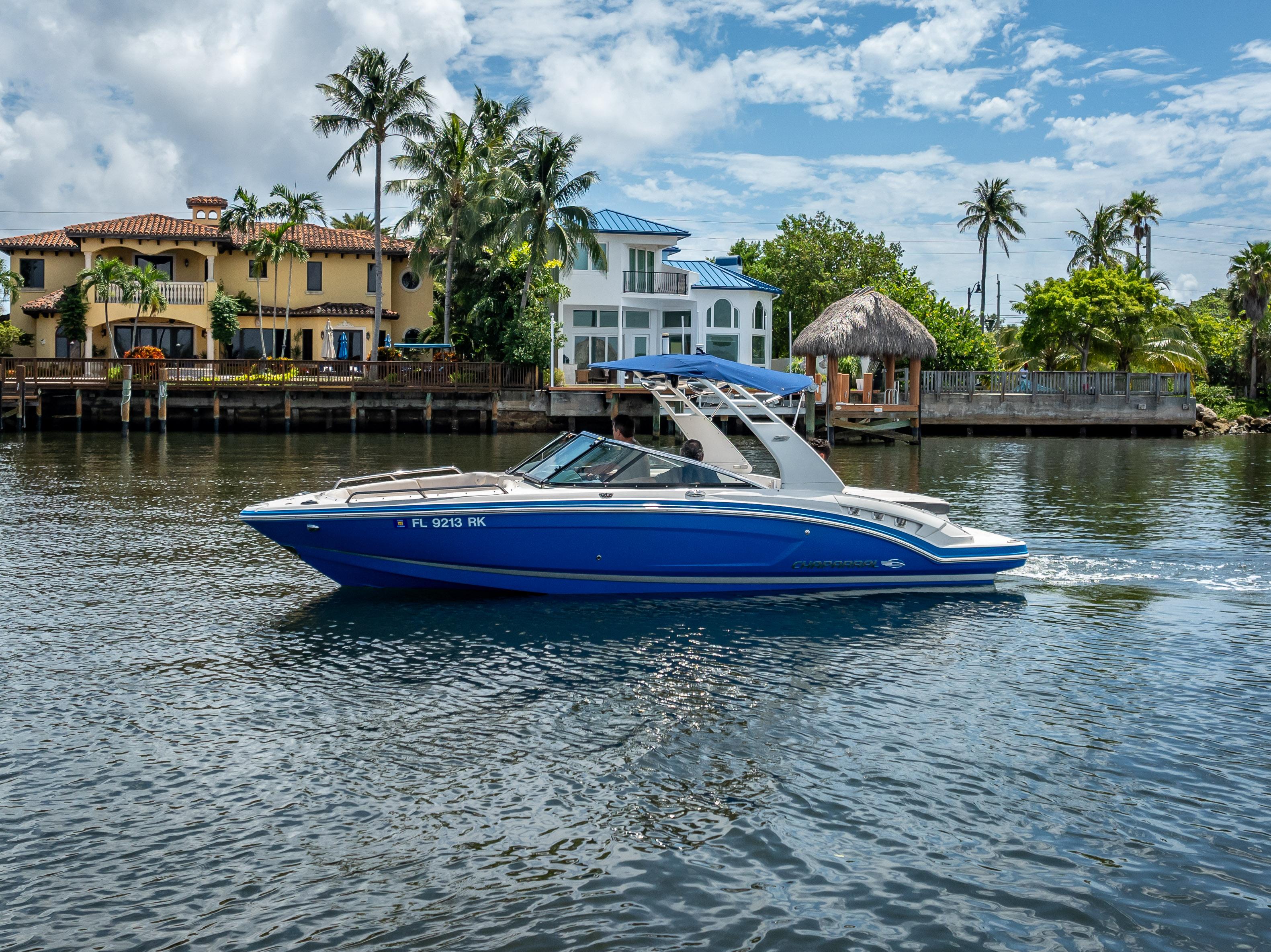2017 Chaparral 227 SSX boat cruising on a sunny waterfront with palm trees.