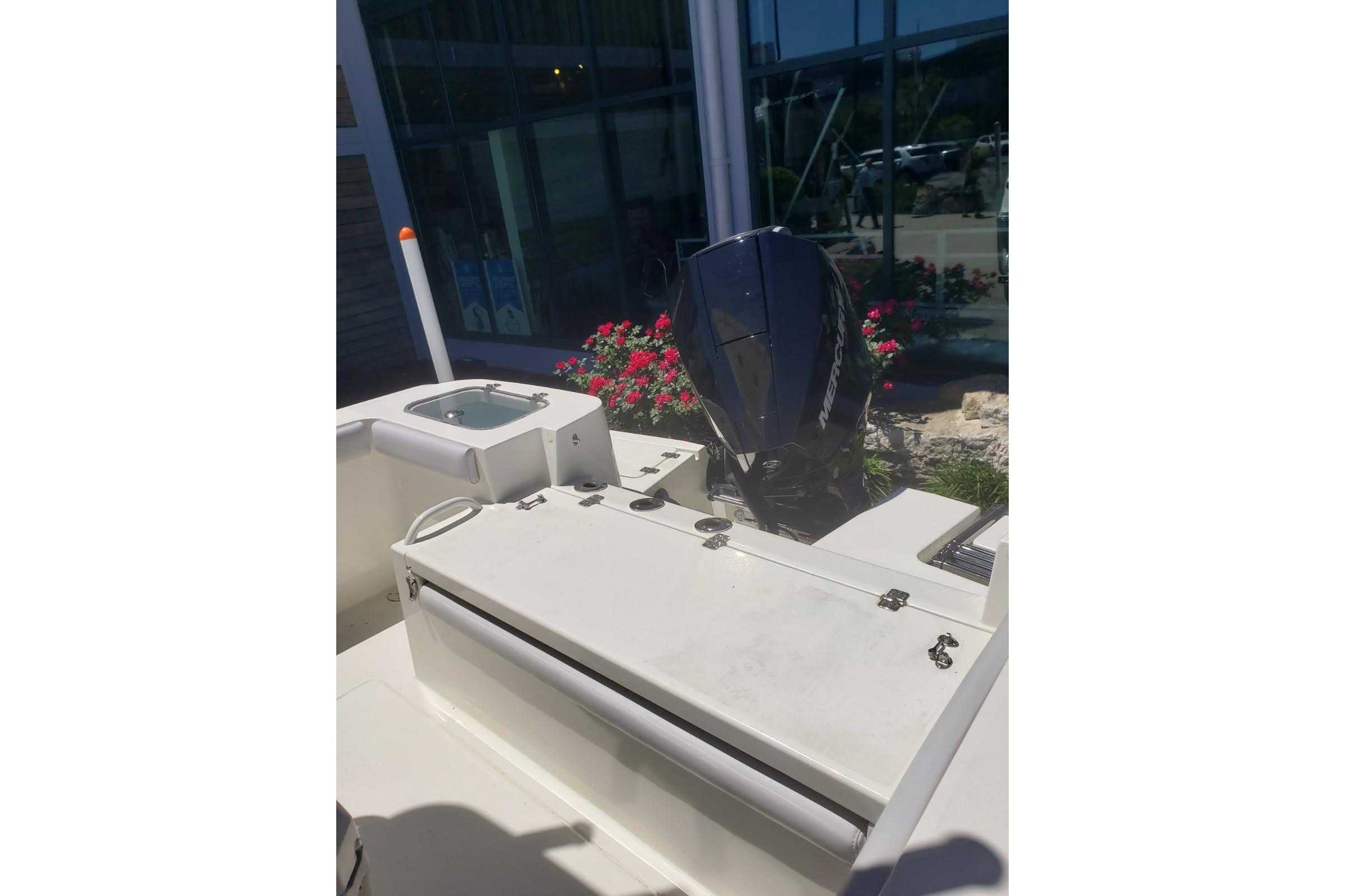 2026 Mako 226 Center Console boat with outboard motor, docked near flowers.