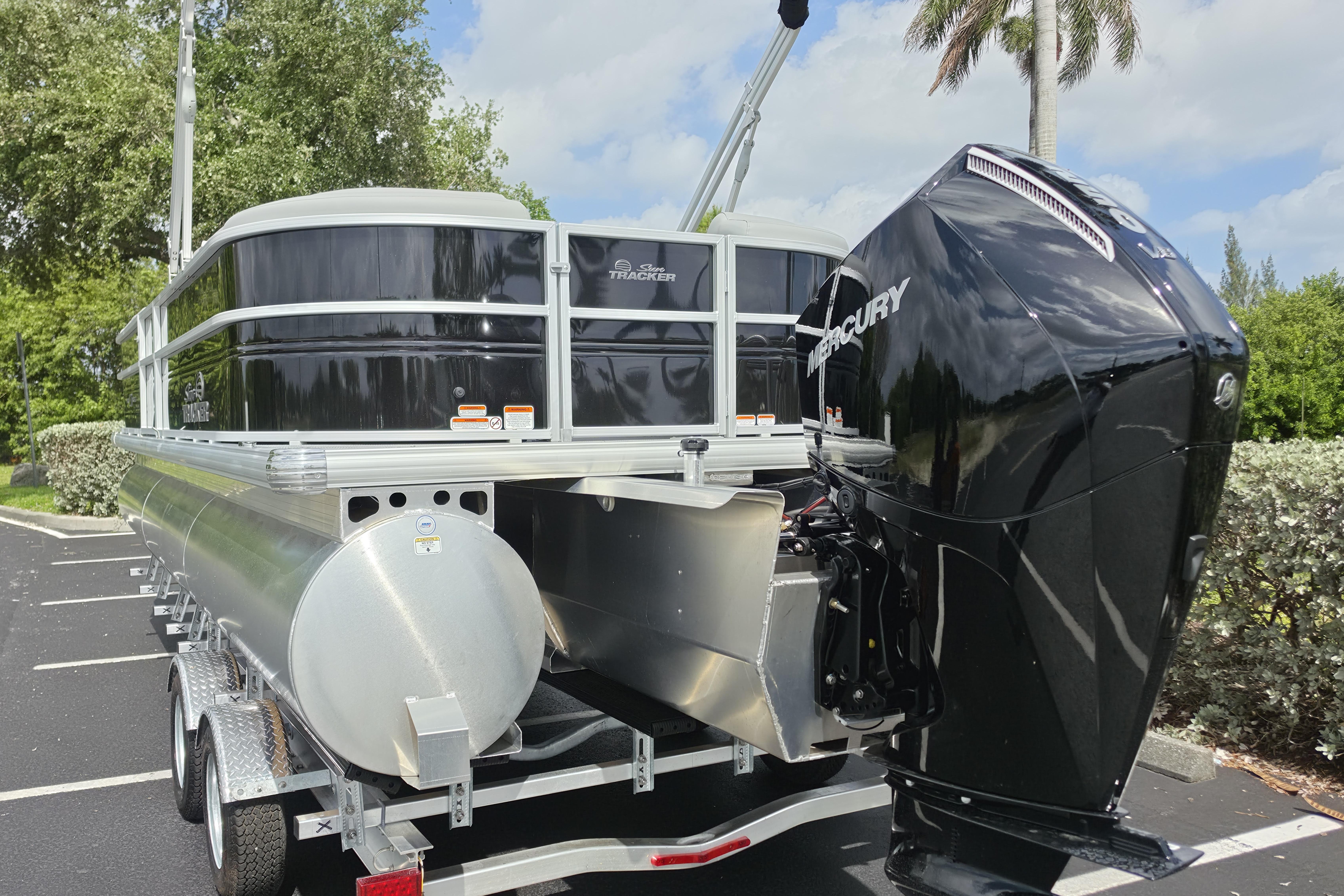 2026 Sun Tracker Party Barge 24 XP3 pontoon boat with Mercury engine in a parking lot.