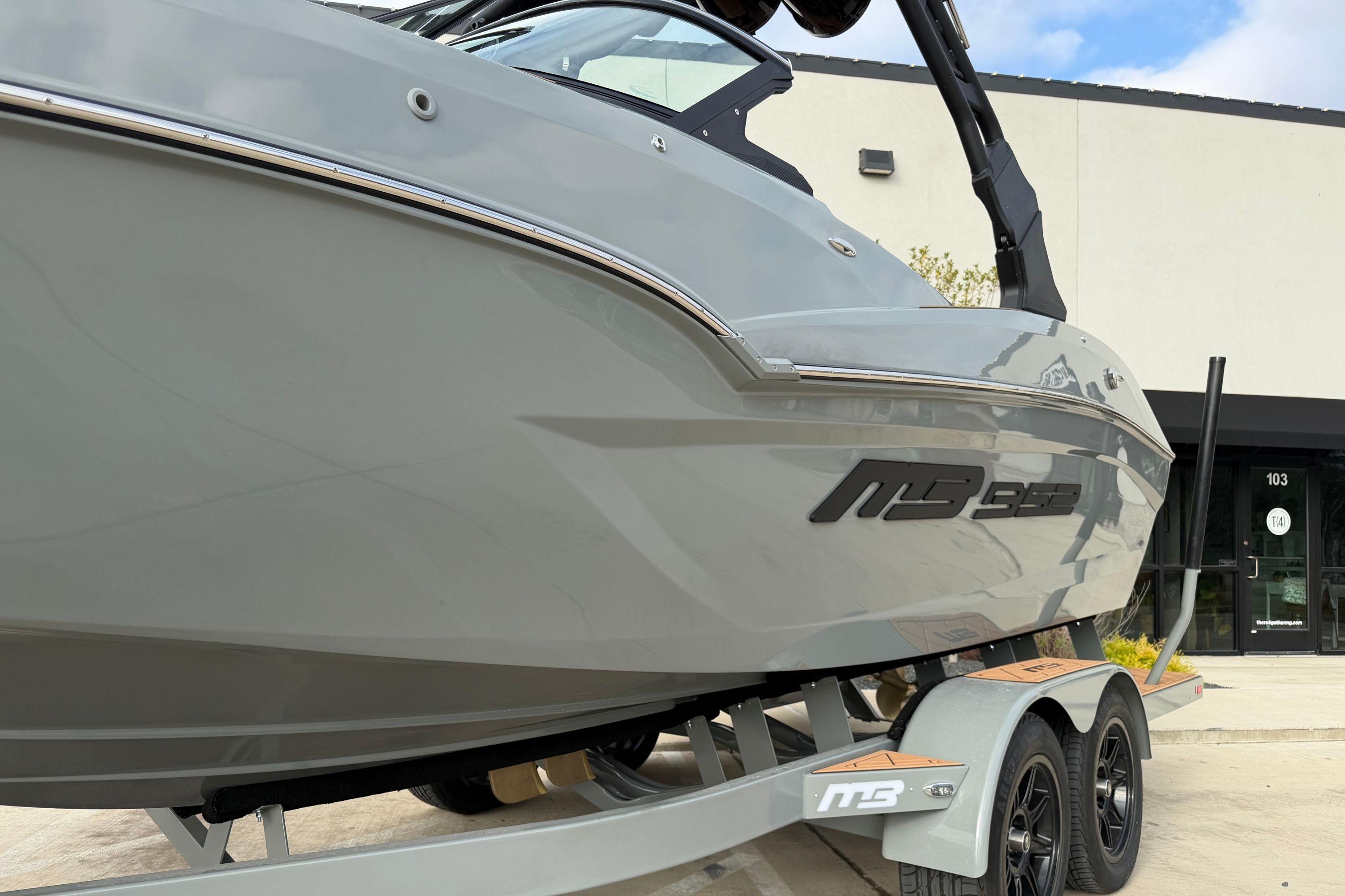 2026 MB B52 21 Alpha boat on trailer, sleek design, parked outside building.