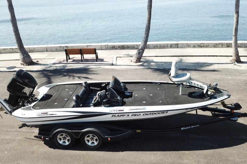 2005 Triton Tr-21X PD boat parked by waterfront with palm trees.