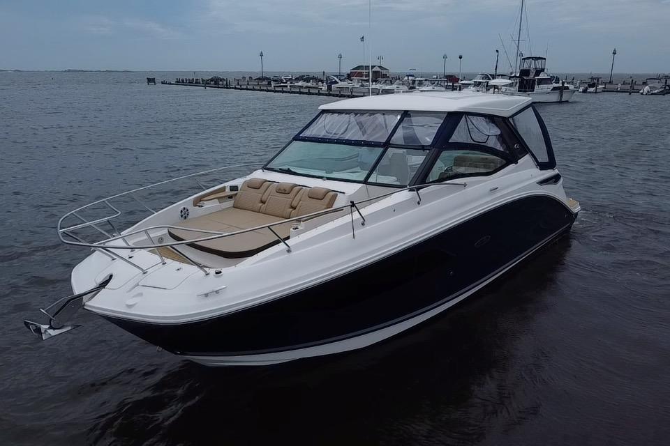 2021 Sea Ray Sundancer 320 Outboard boat on calm waters near a marina.