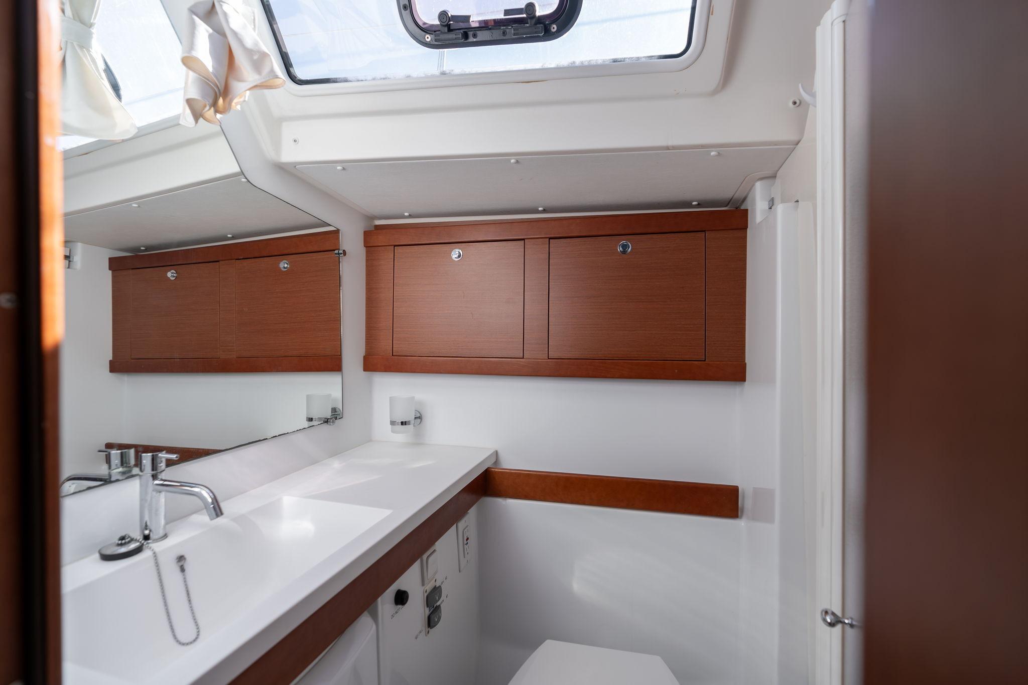 Interior of 2013 Beneteau Oceanis 50 yacht bathroom with wooden cabinets and modern fixtures.