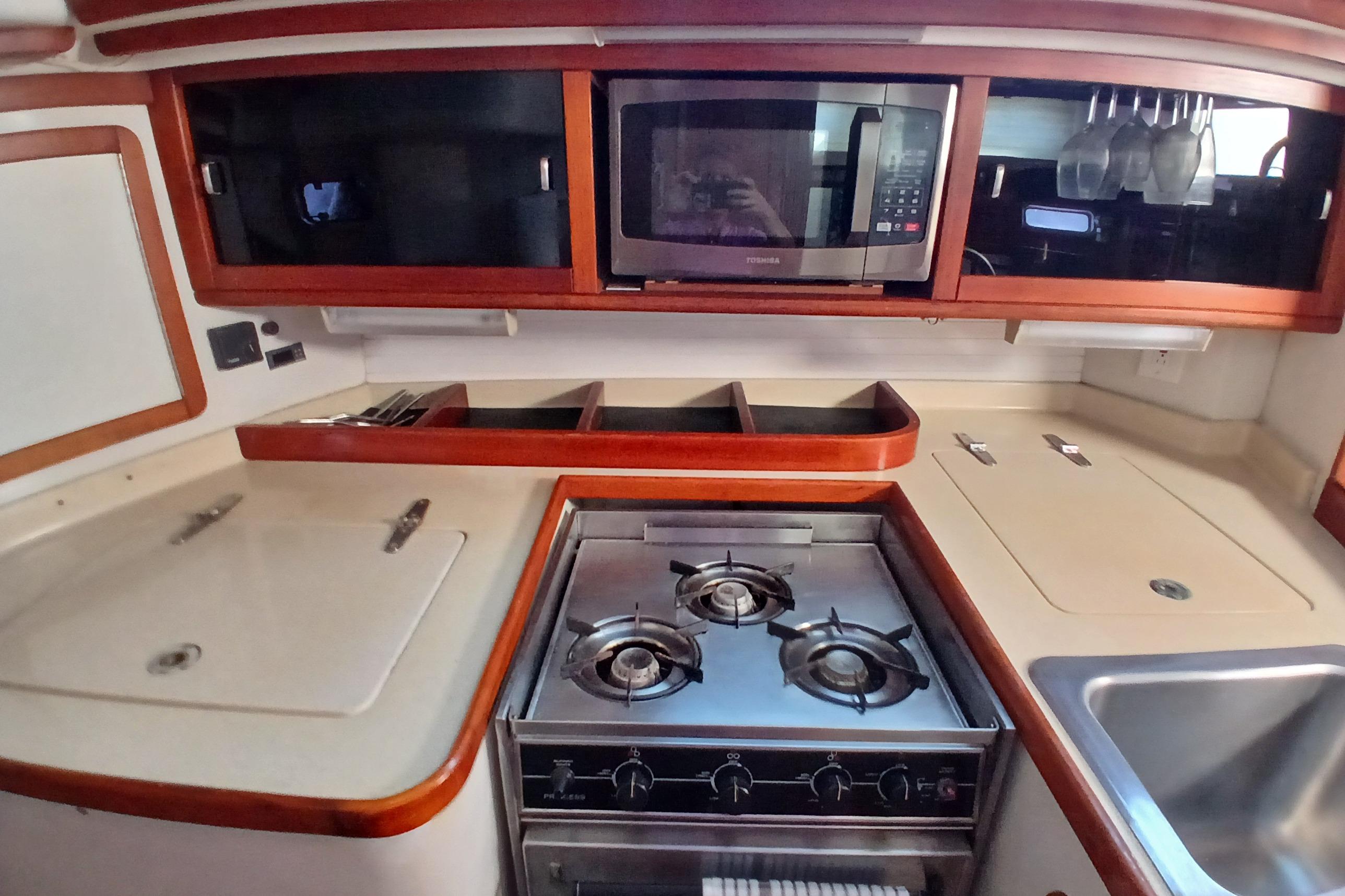Galley kitchen in 1995 Catalina 42 MkII yacht with stove, microwave, and sink.