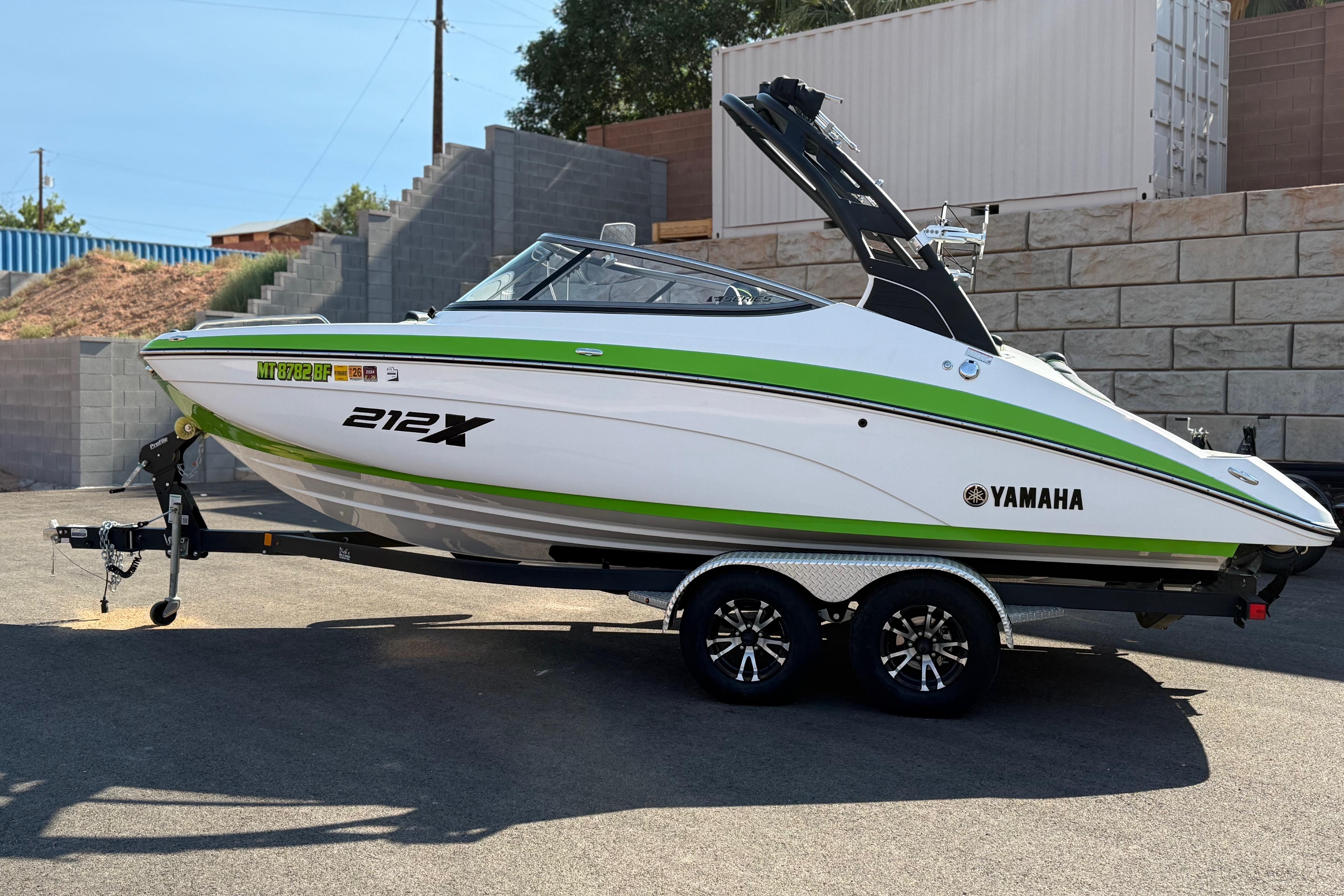 2022 Yamaha Boats 212XE in white and green on a trailer, parked outdoors.