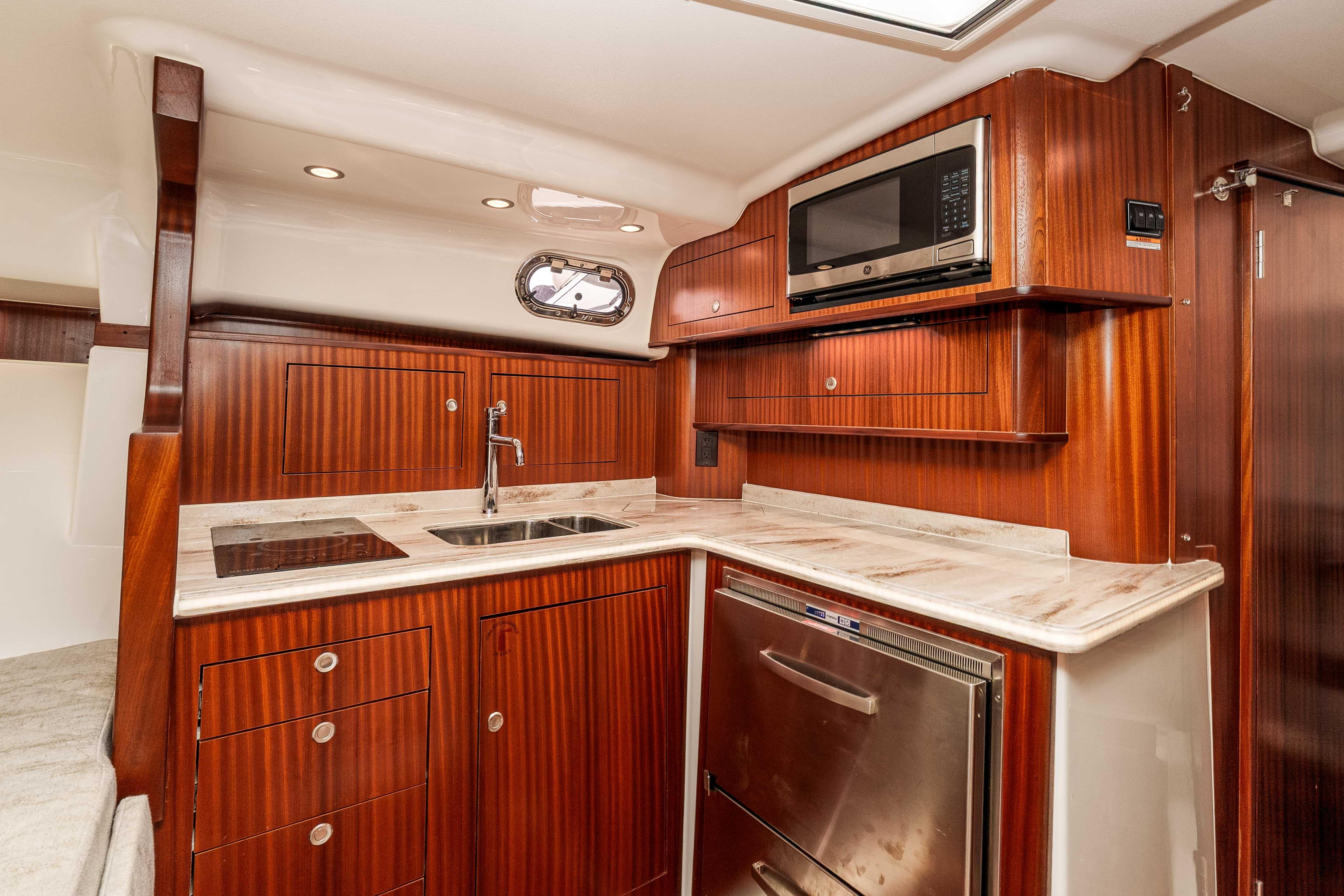 Luxurious 2022 Pursuit OS 385 Offshore yacht kitchen with wood cabinetry and modern appliances.