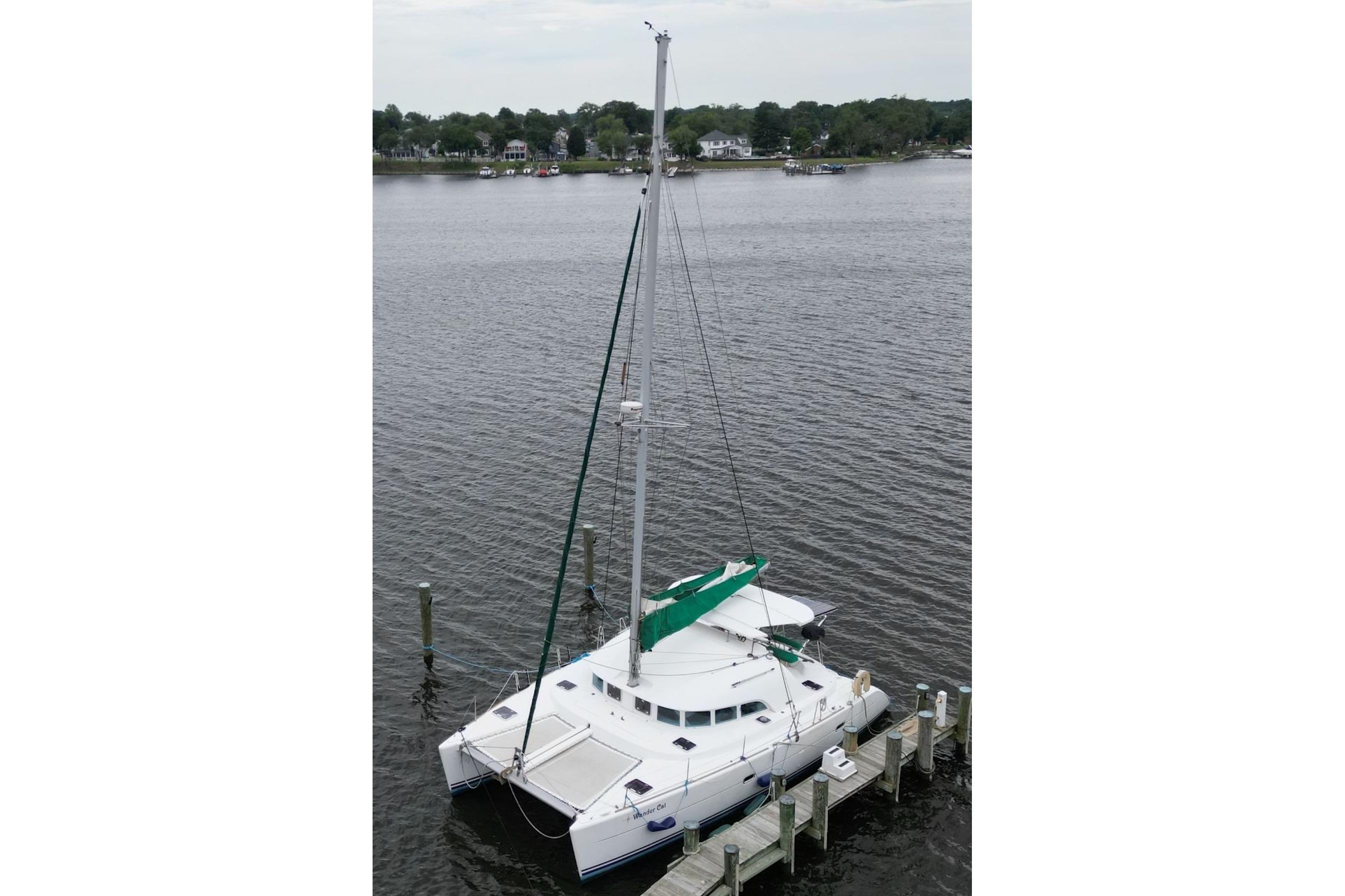 2004 Lagoon 380 catamaran docked on calm waters, featuring a green sail cover.