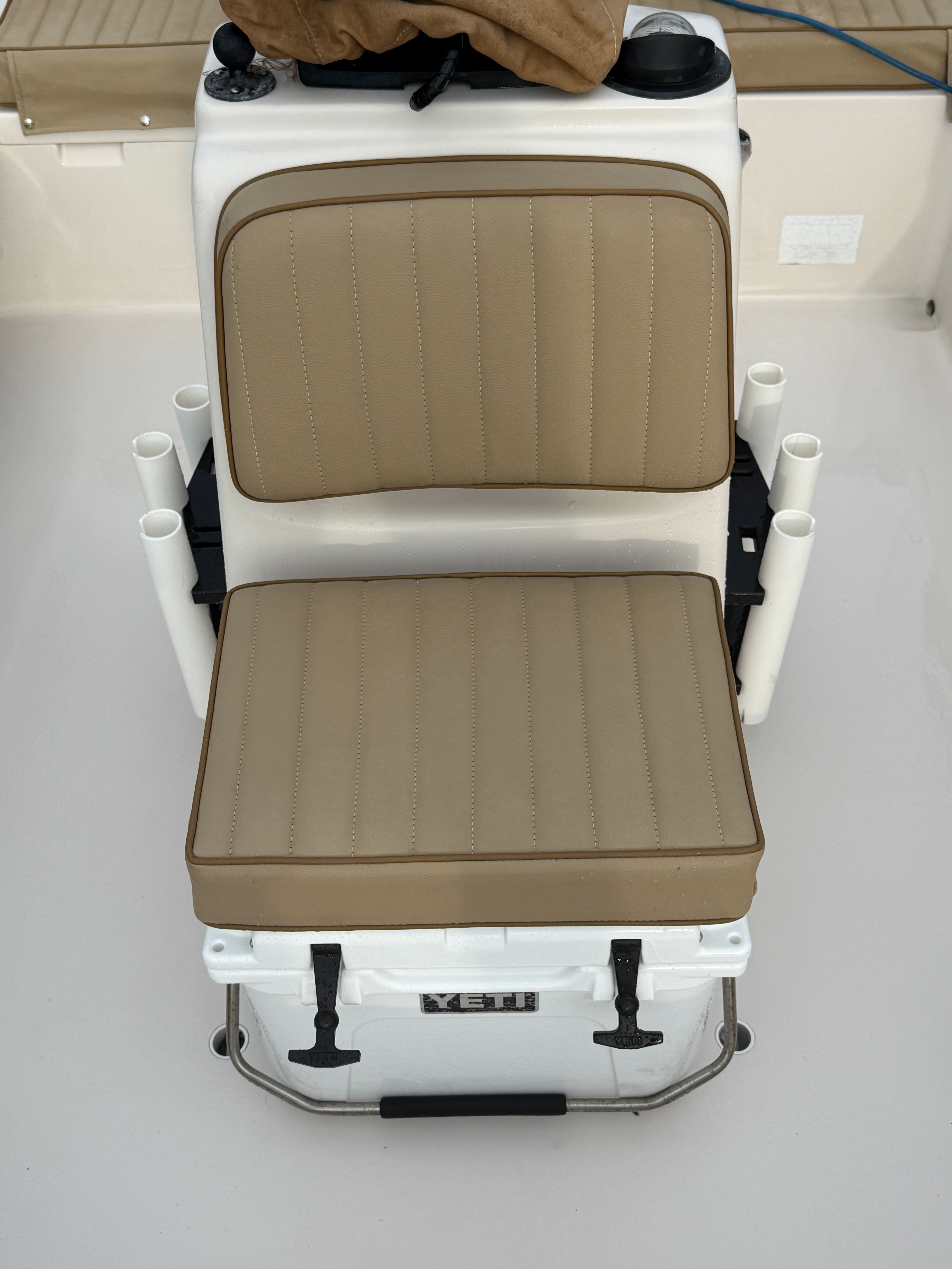 A beige seat cushion on a cooler with fishing rod holders.
