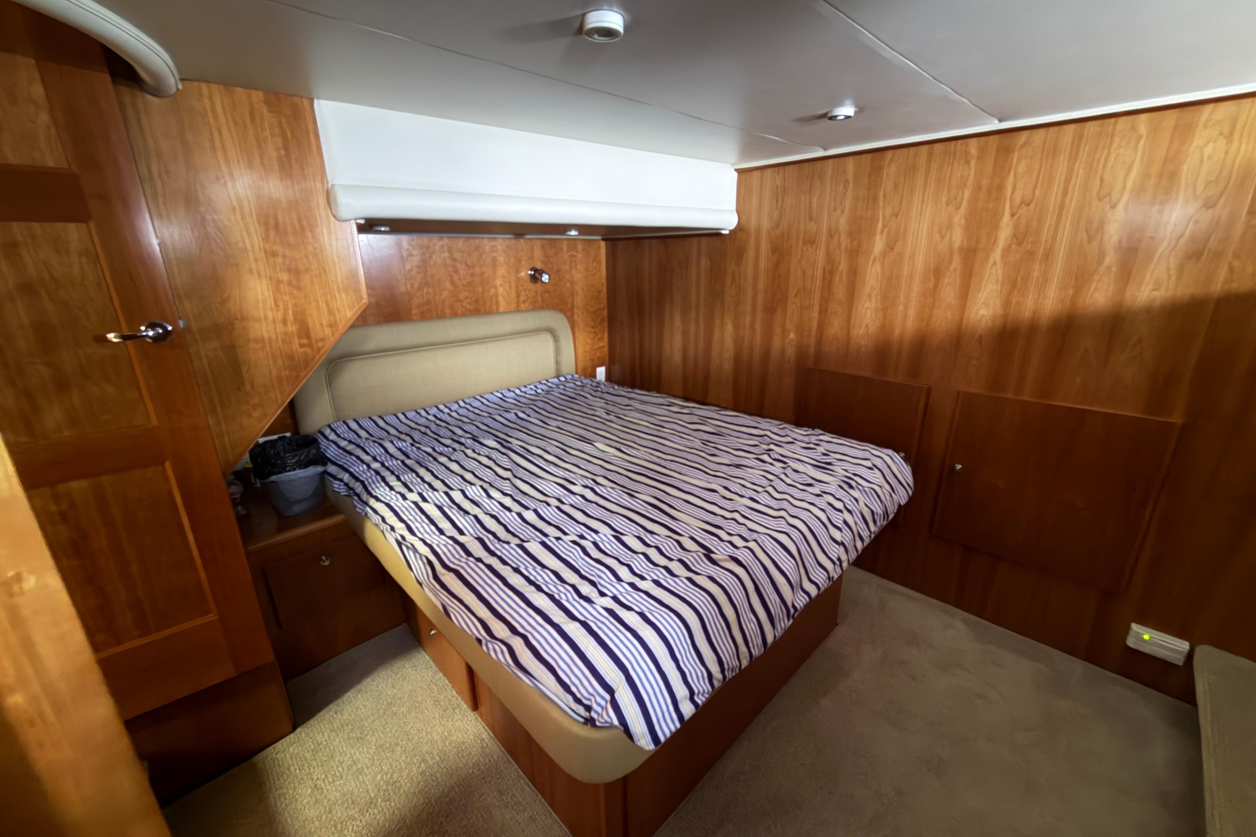 Cozy bedroom with striped bedding in 2005 Navigator 53 Pilot House yacht.