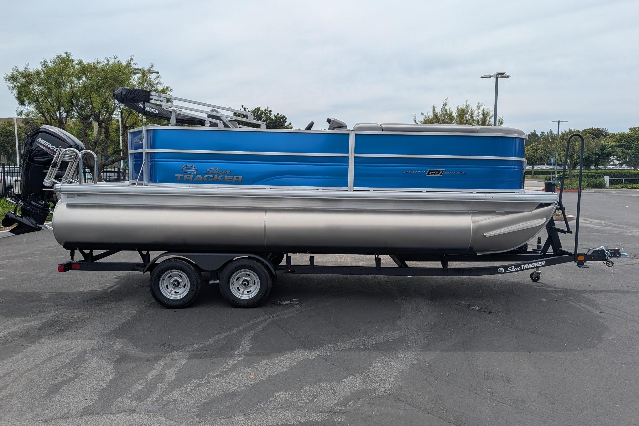 2026 Sun Tracker Party Barge 20 DLX pontoon boat on trailer in parking lot.