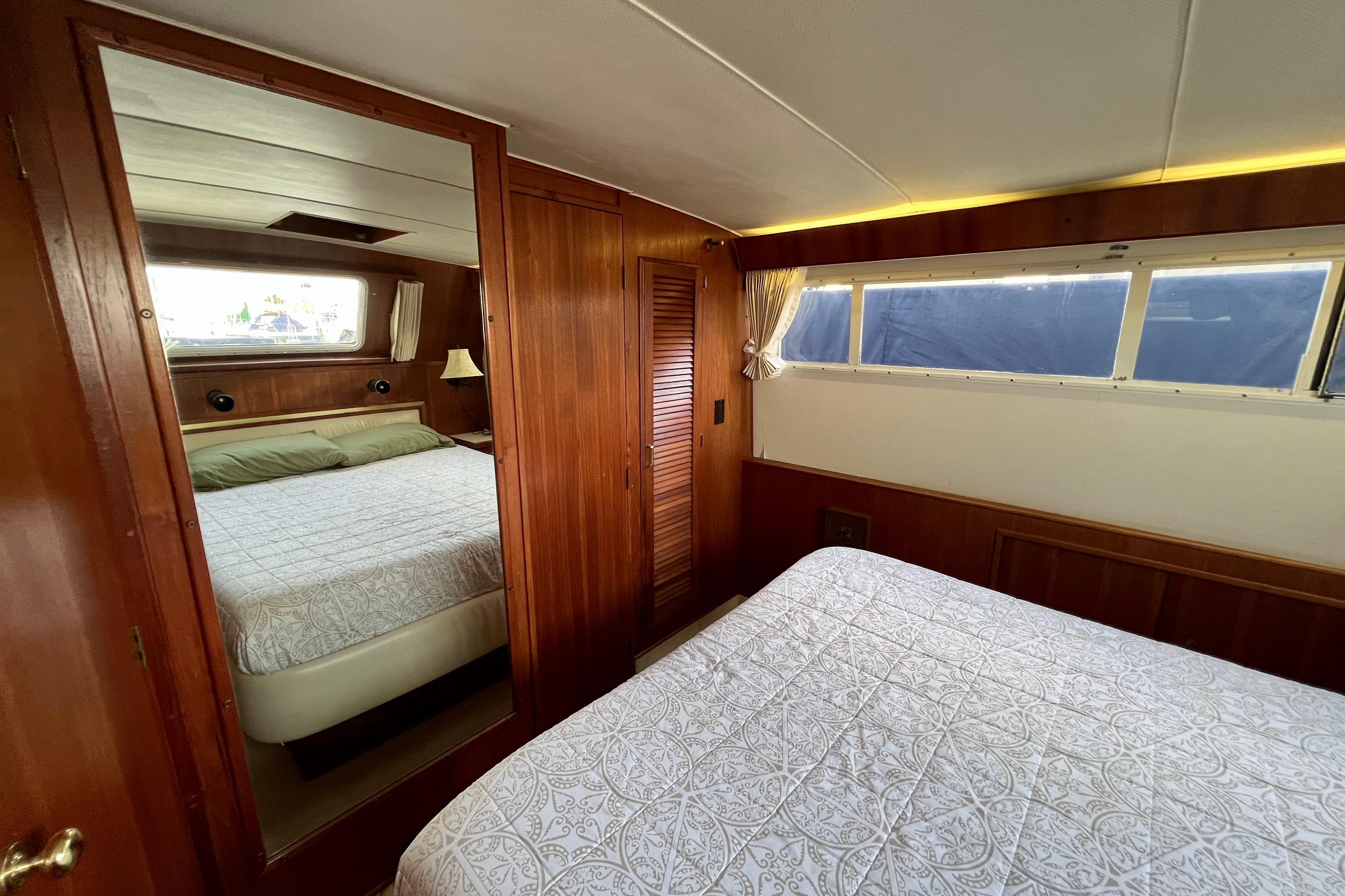 Interior of 1985 Tollycraft 48 Cockpit Motor Yacht with wood paneling and cozy bedding.