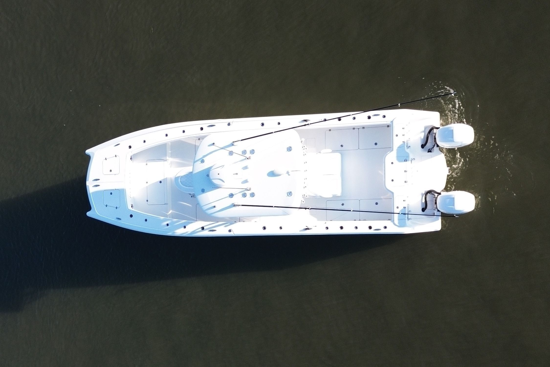 Aerial view of a white boat with two outboard motors on calm water.