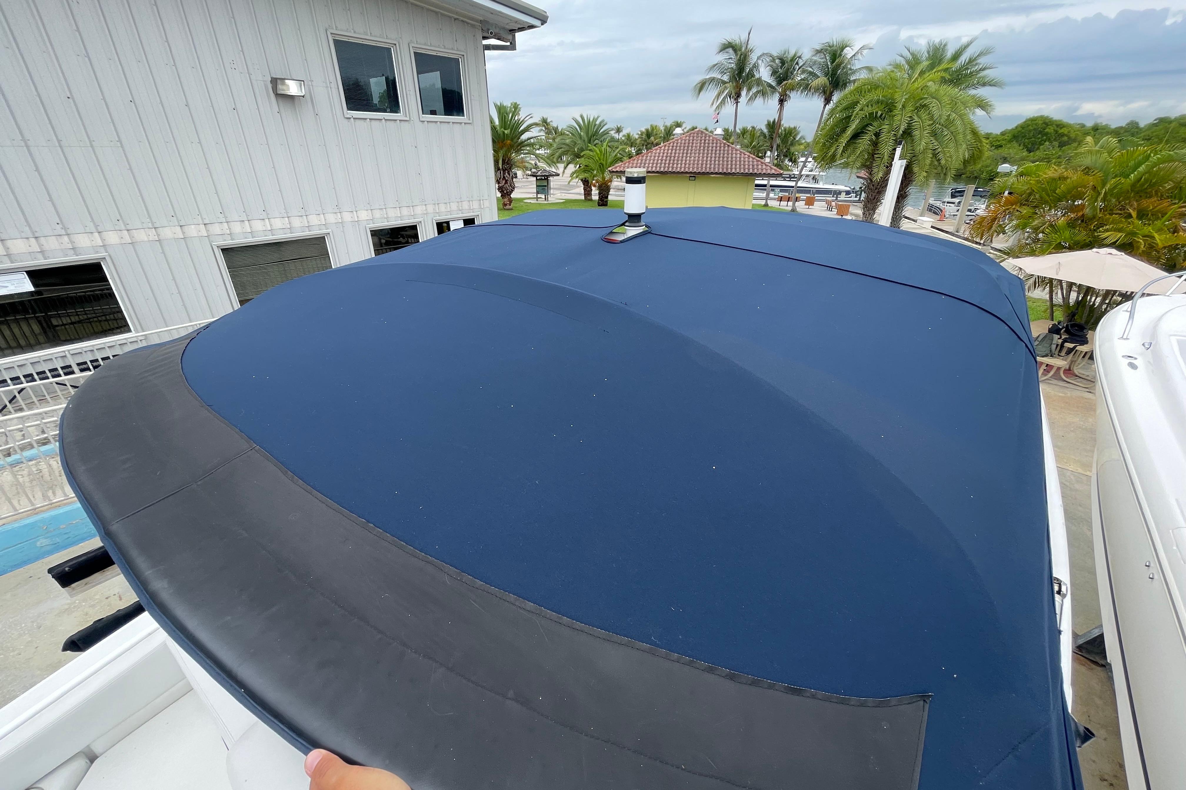 2022 Four Winns HD8 OB boat with blue cover, docked near palm trees.