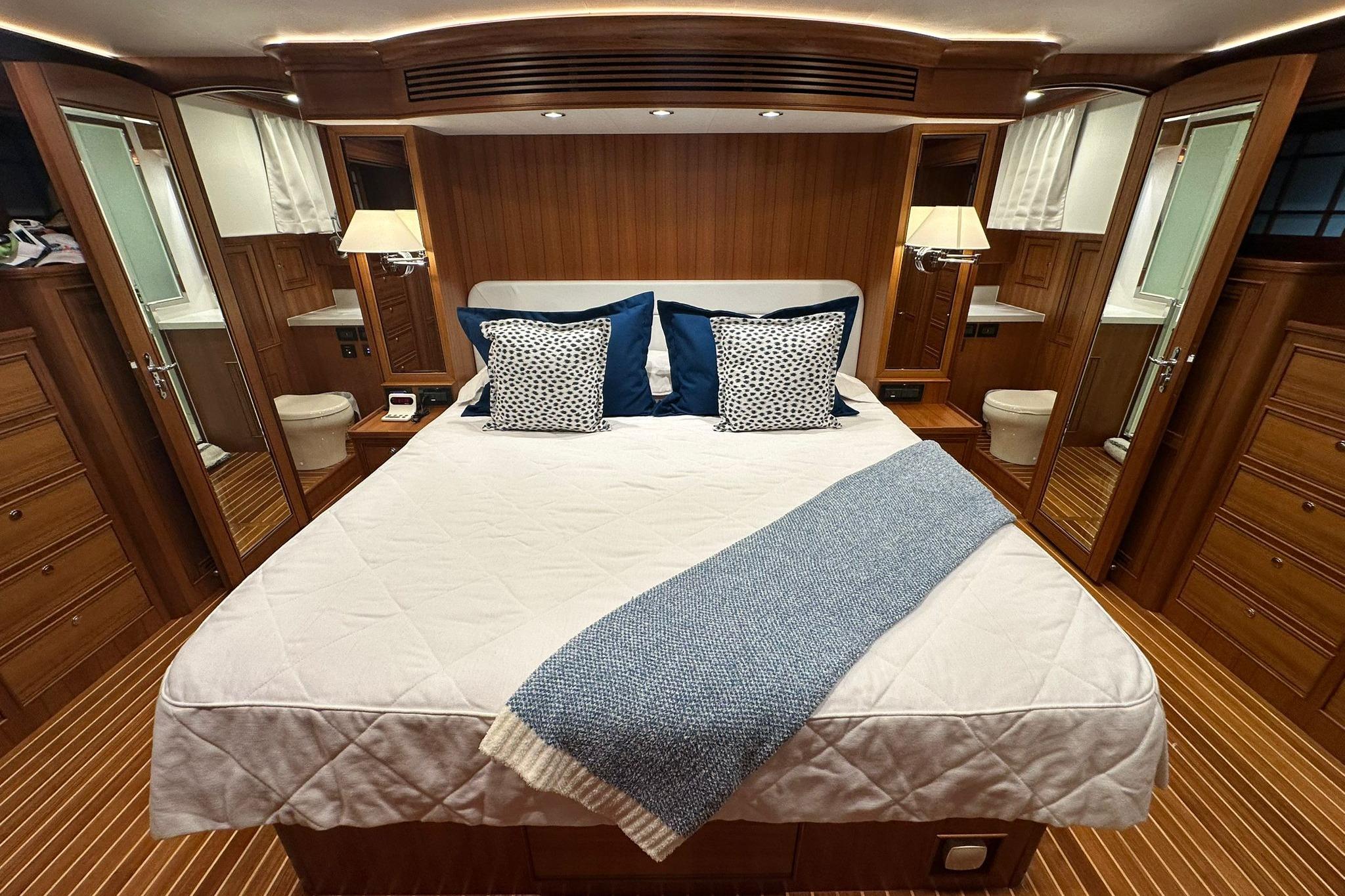 Luxurious bedroom interior of 2023 Marlow Explorer 66E-CB yacht with elegant wood finish.