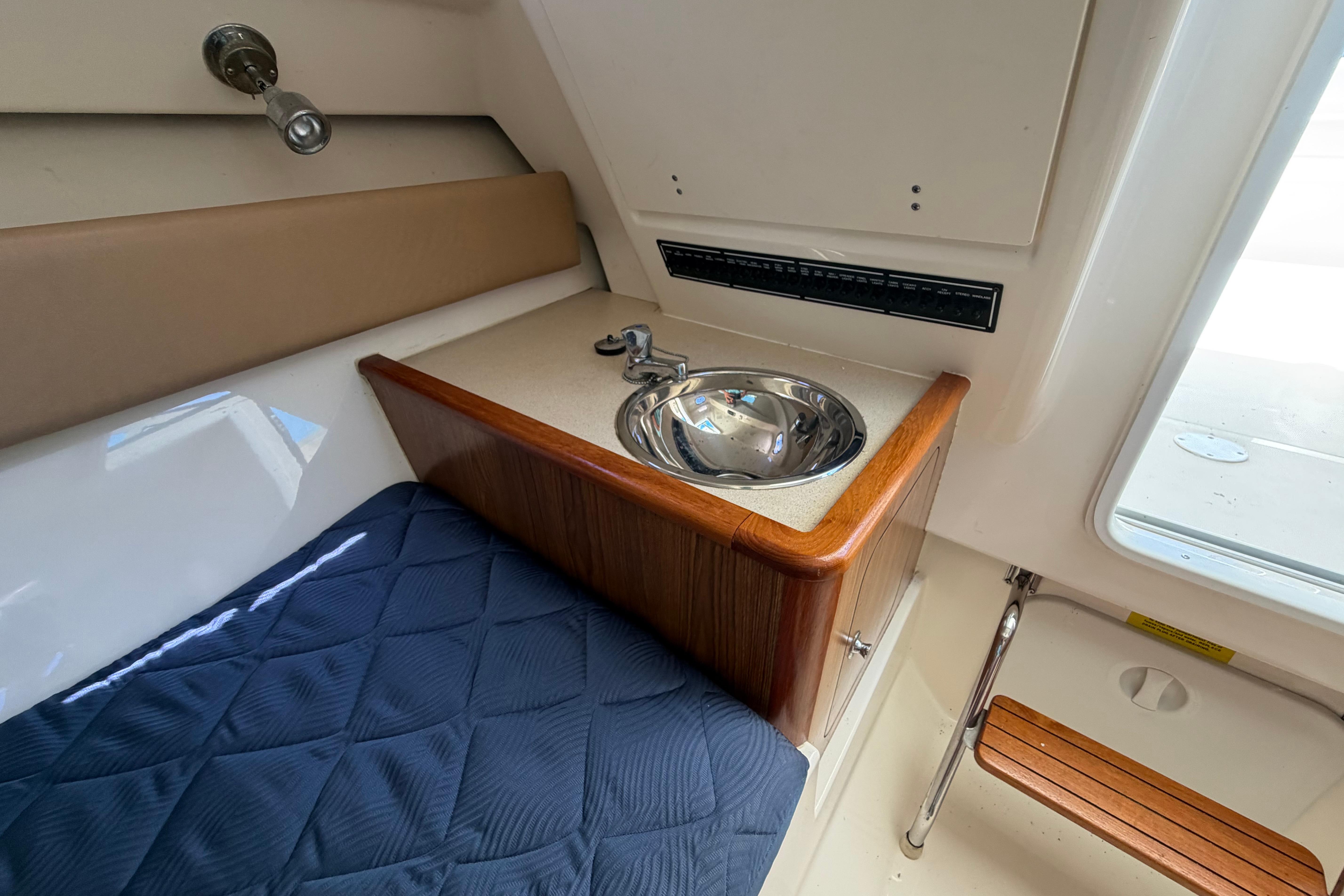 2010 Pursuit OS 255 Offshore cabin interior with sink and cushioned seating.