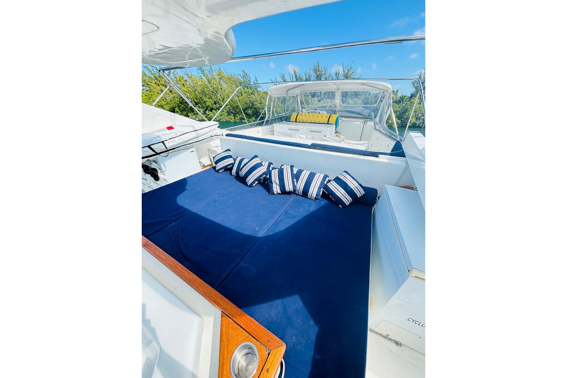 Luxurious Falcon 100 yacht deck with blue cushions, striped pillows, and scenic background.