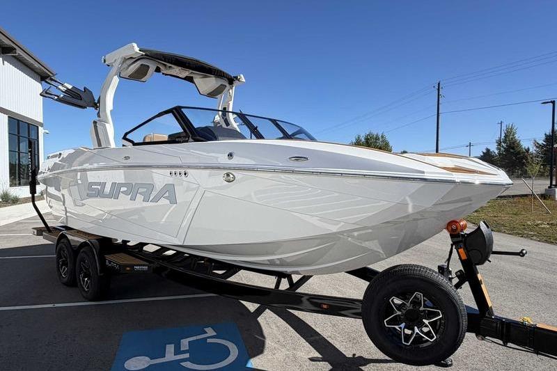 2026 Supra SL boat on trailer, parked outdoors under clear blue sky.