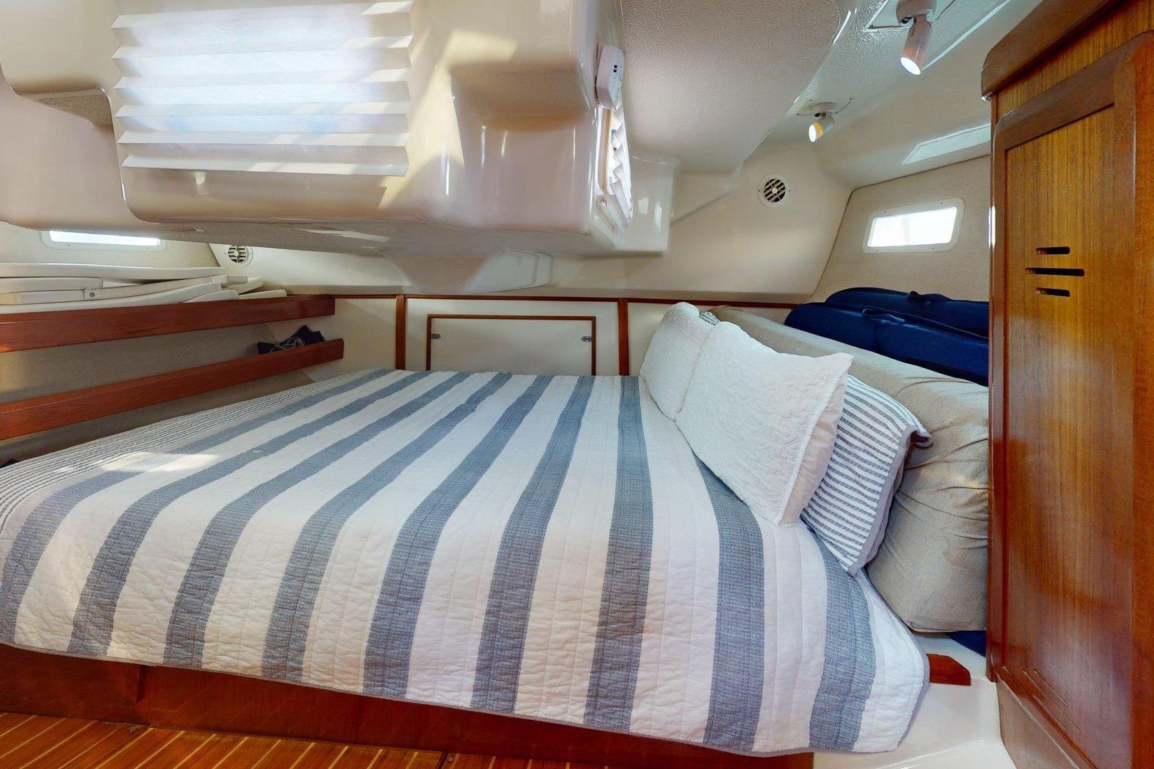 Cozy cabin interior of 1997 Hunter Legend 40.5 sailboat with striped bedding and wooden accents.