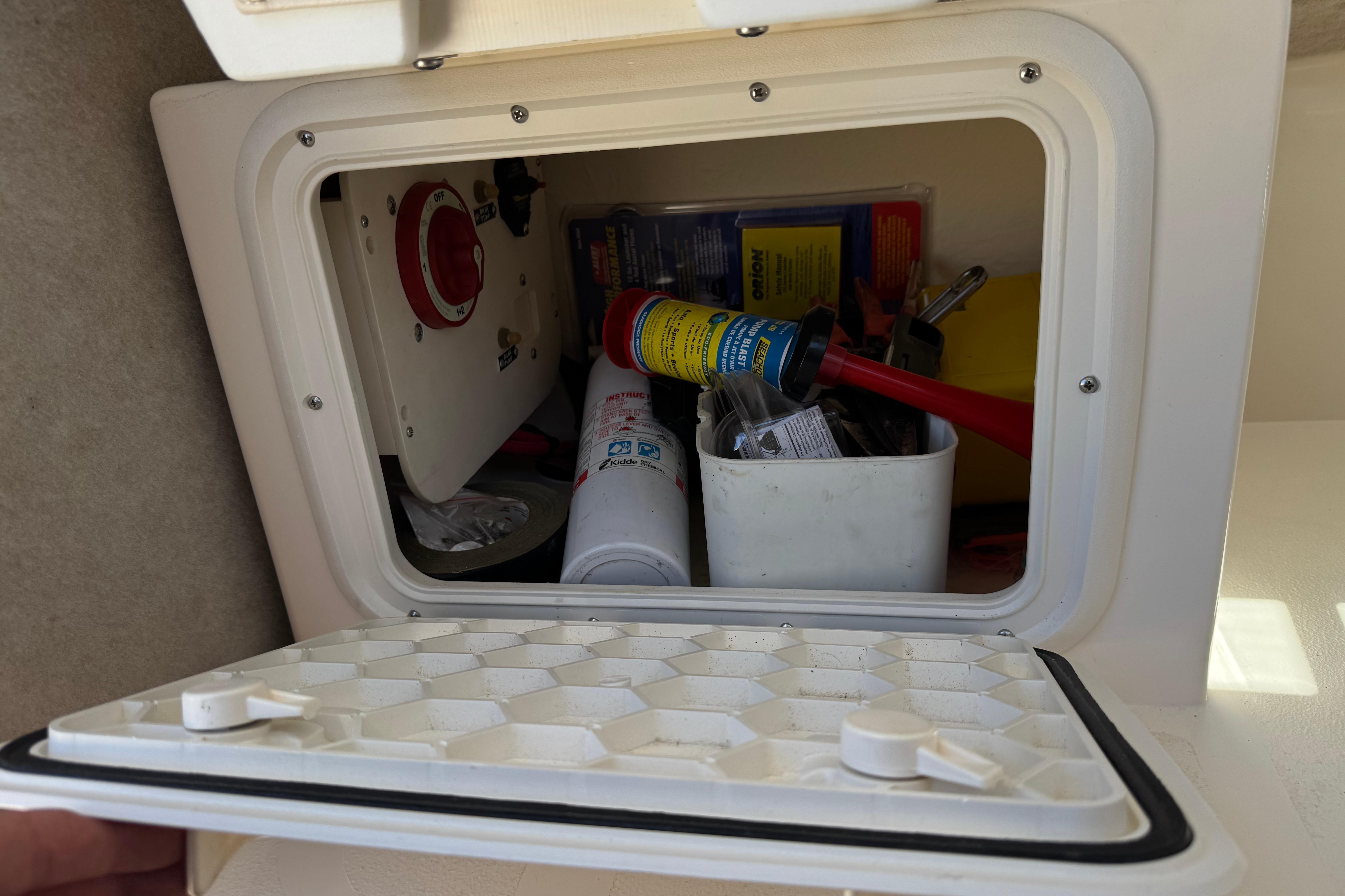 Storage compartment of a 2017 Defiance Admiral 220 EX boat, containing tools and supplies.
