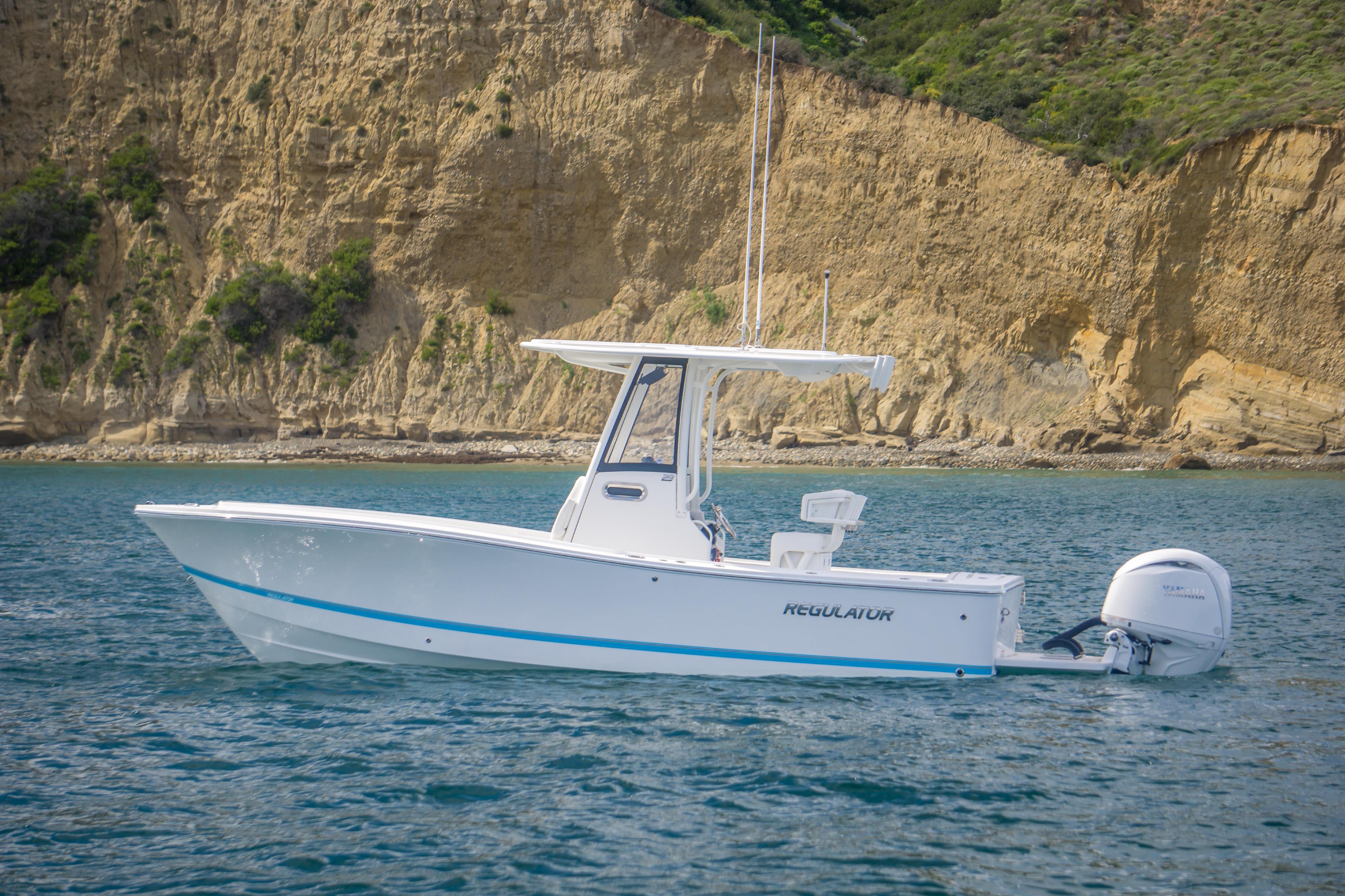 2026 Regulator 23 boat on water near rocky cliff background.