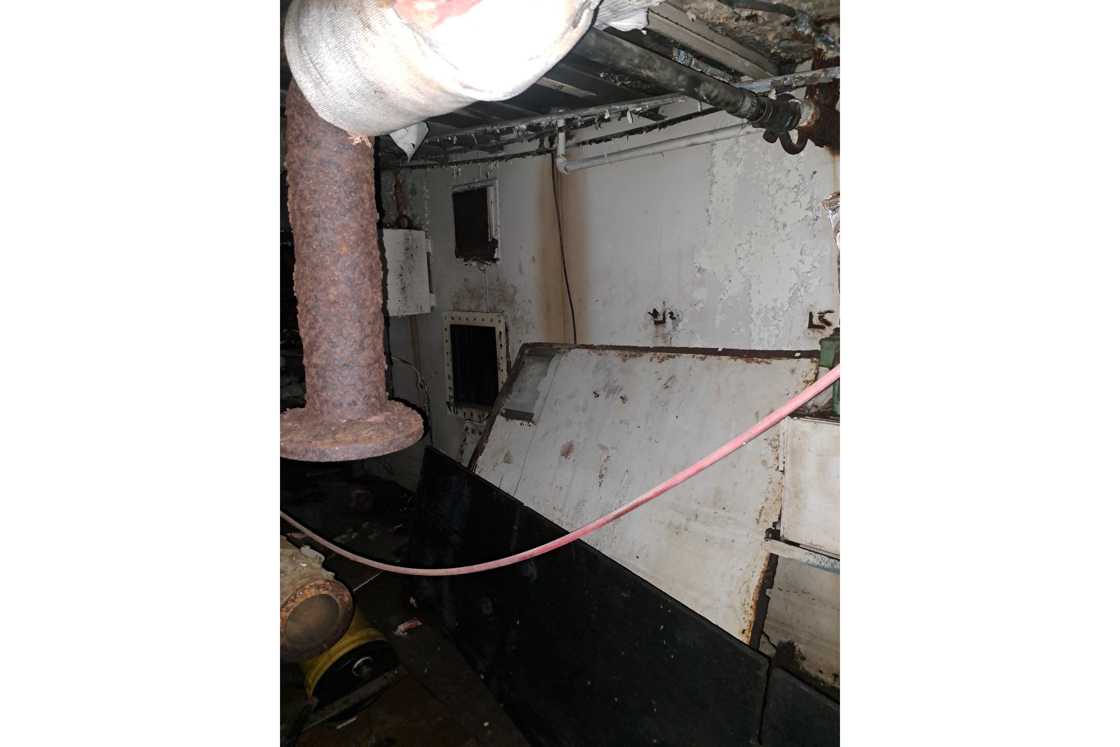 Interior of a 1979 Custom Steel Trawler Dragger, showing rusted pipes and worn surfaces.