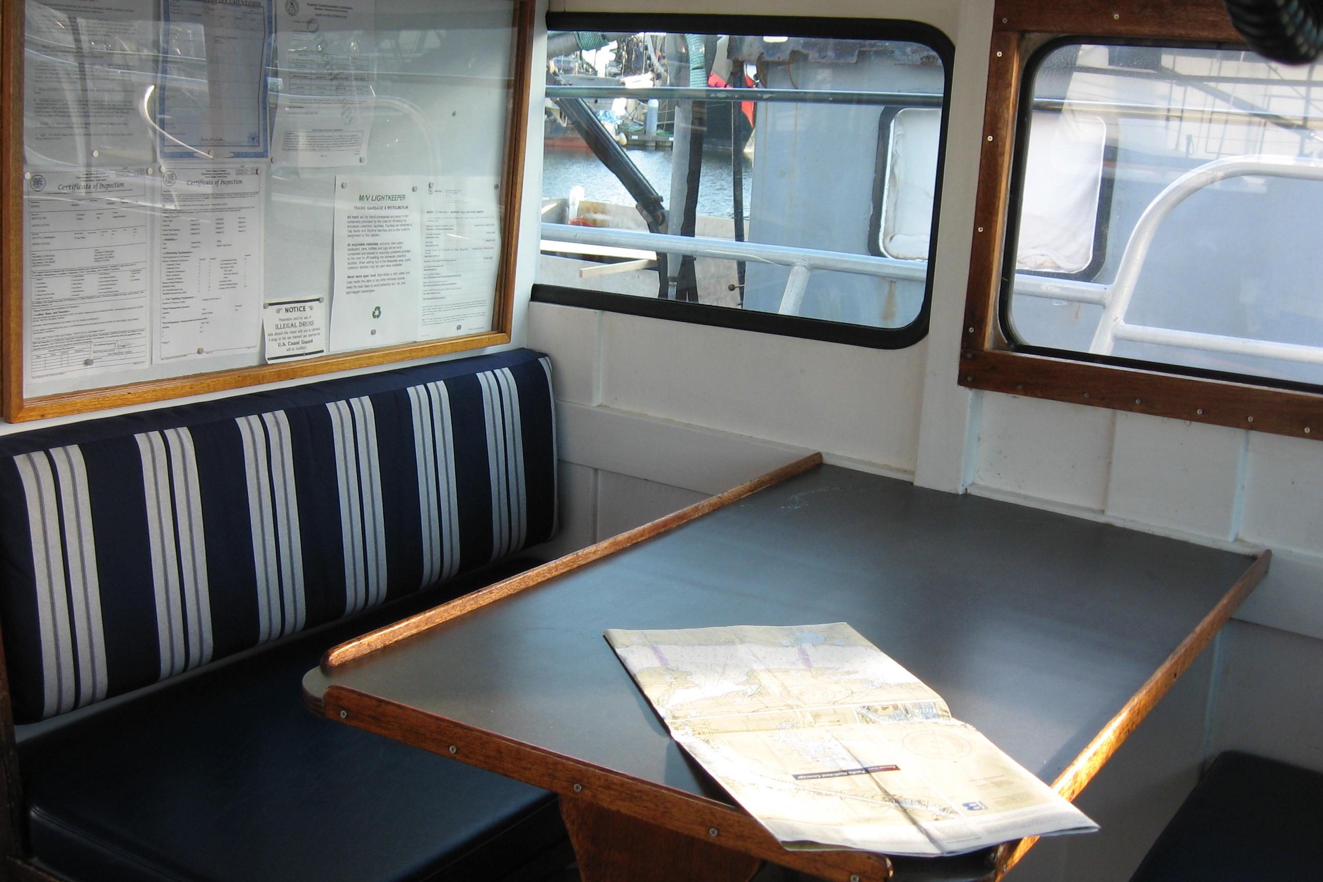 Interior of a 1964 Grandy Tour Boat with striped seating and a map on the table.