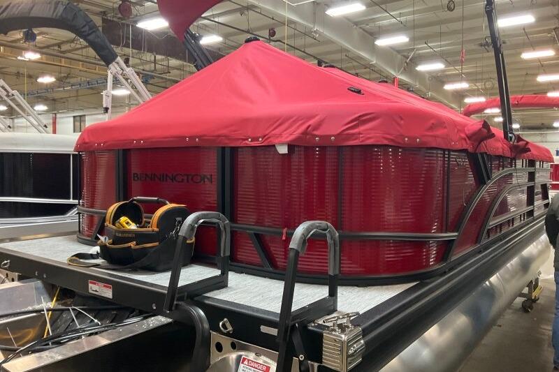 2026 Bennington 22 SSRSF pontoon boat with red cover in a showroom.