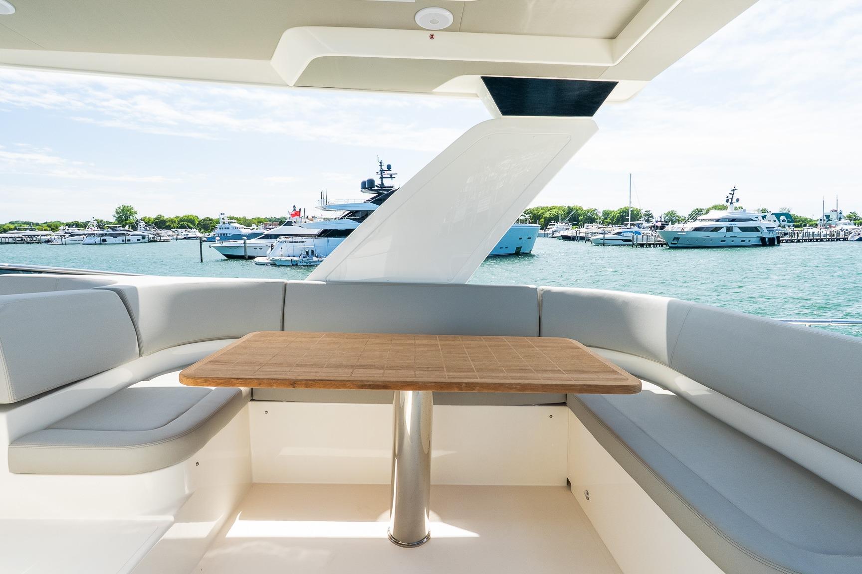 Luxurious seating area on 2026 Absolute Navetta 53 yacht, overlooking marina with multiple boats.