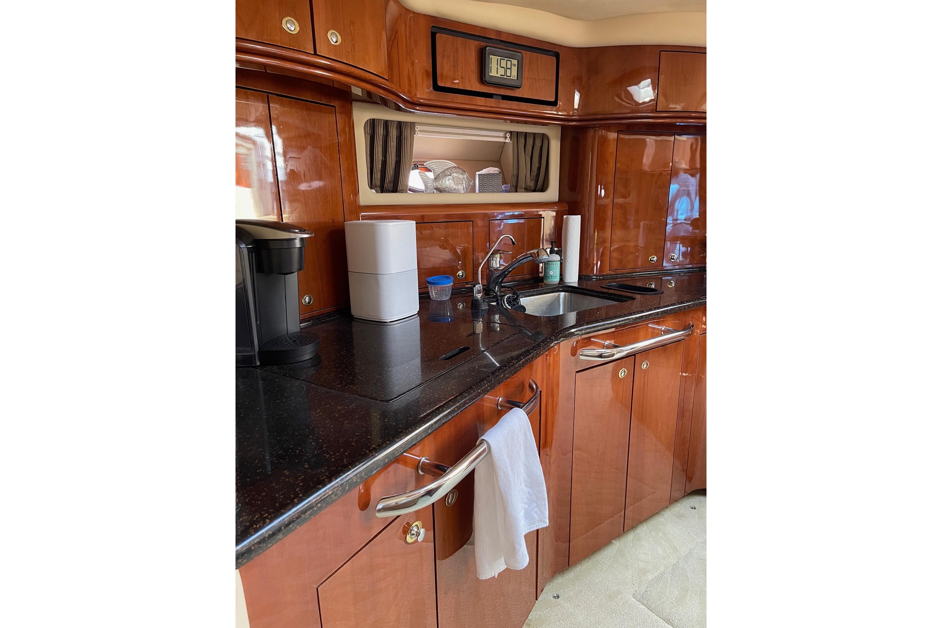 Luxurious 2003 Sea Ray 550 Sundancer yacht kitchen with sleek wood cabinetry and modern appliances.