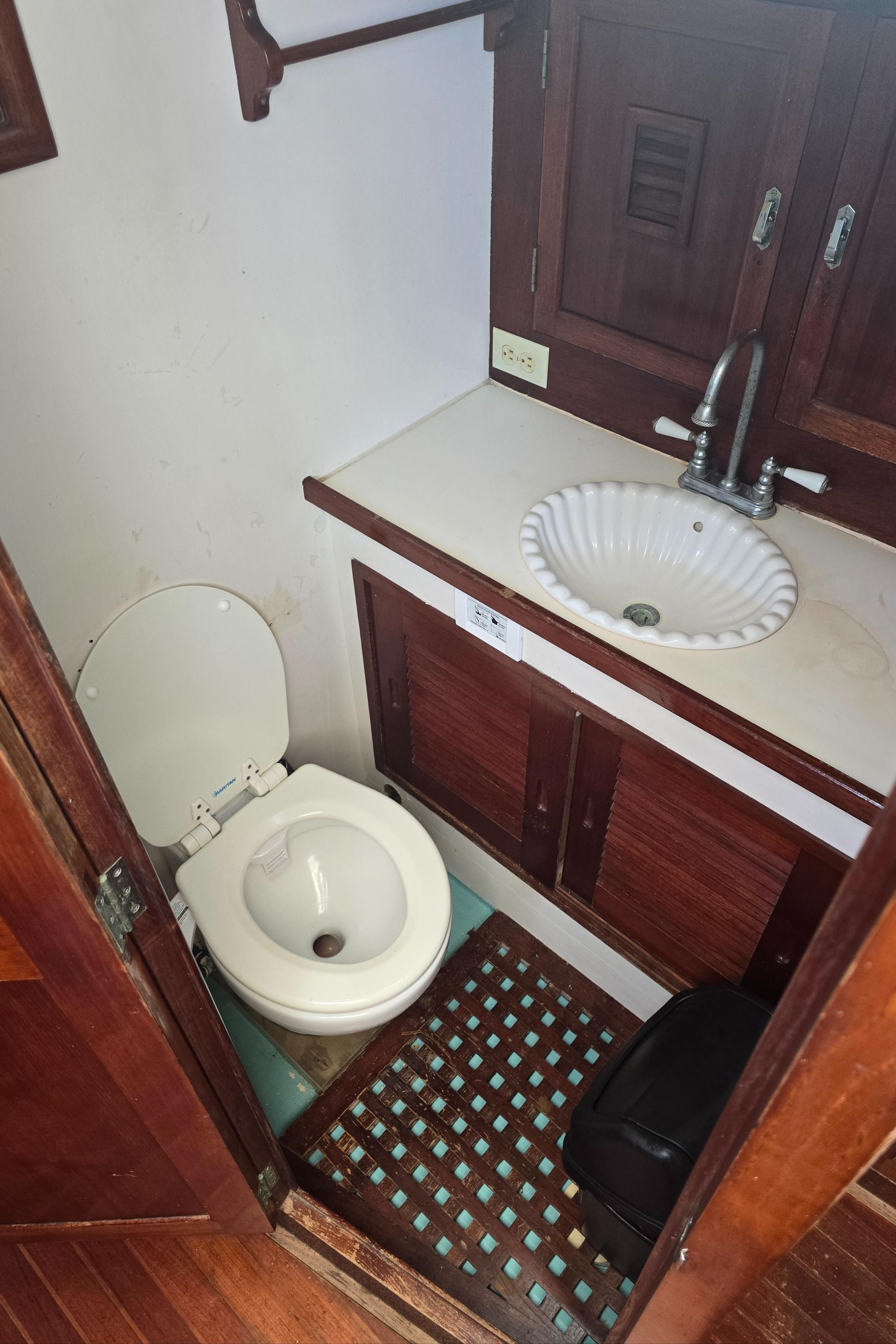 1978 Herreshoff 50 yacht bathroom with wooden cabinetry, sink, and toilet.