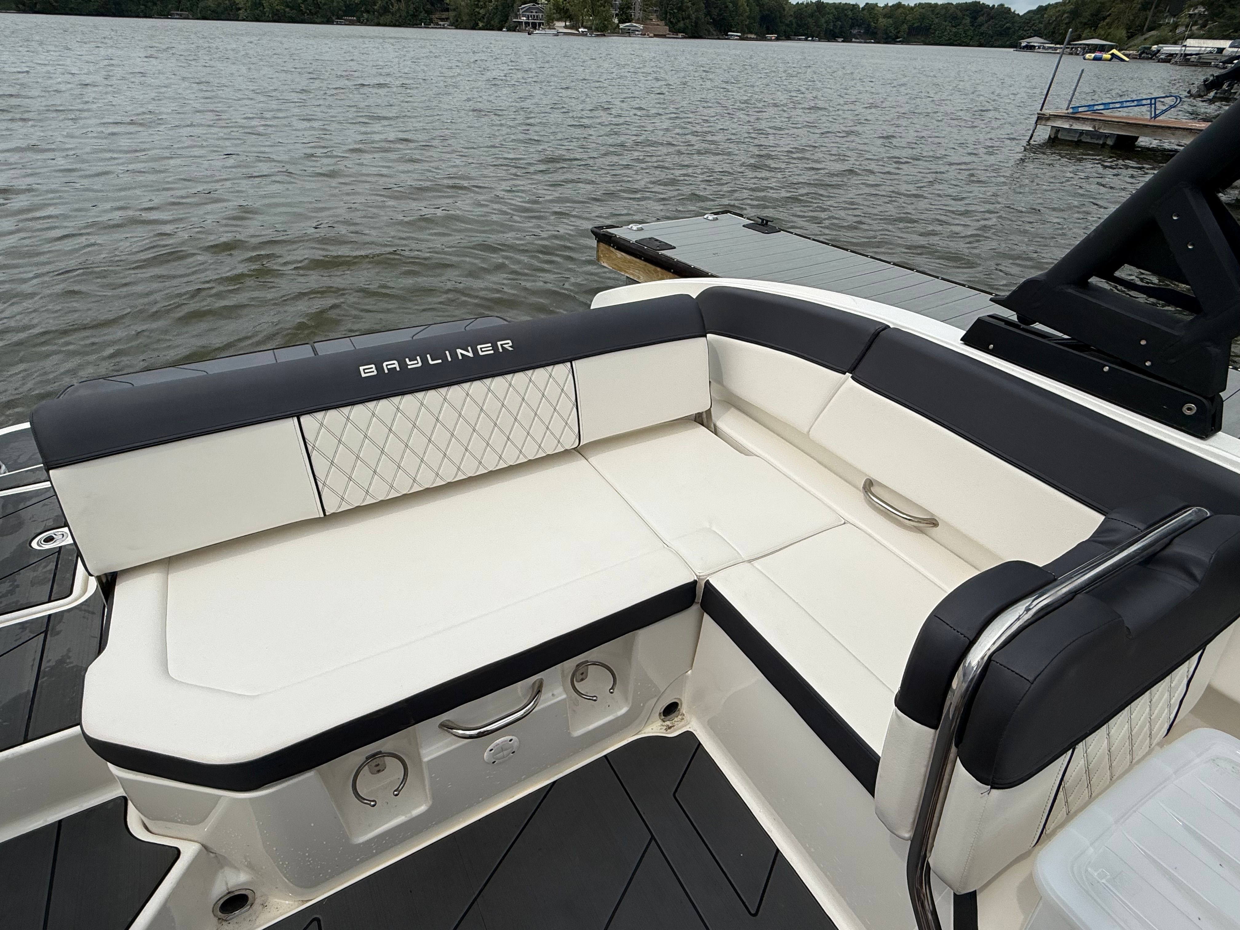 2022 Bayliner DX 2250 boat with white and black seating, docked by a lake.