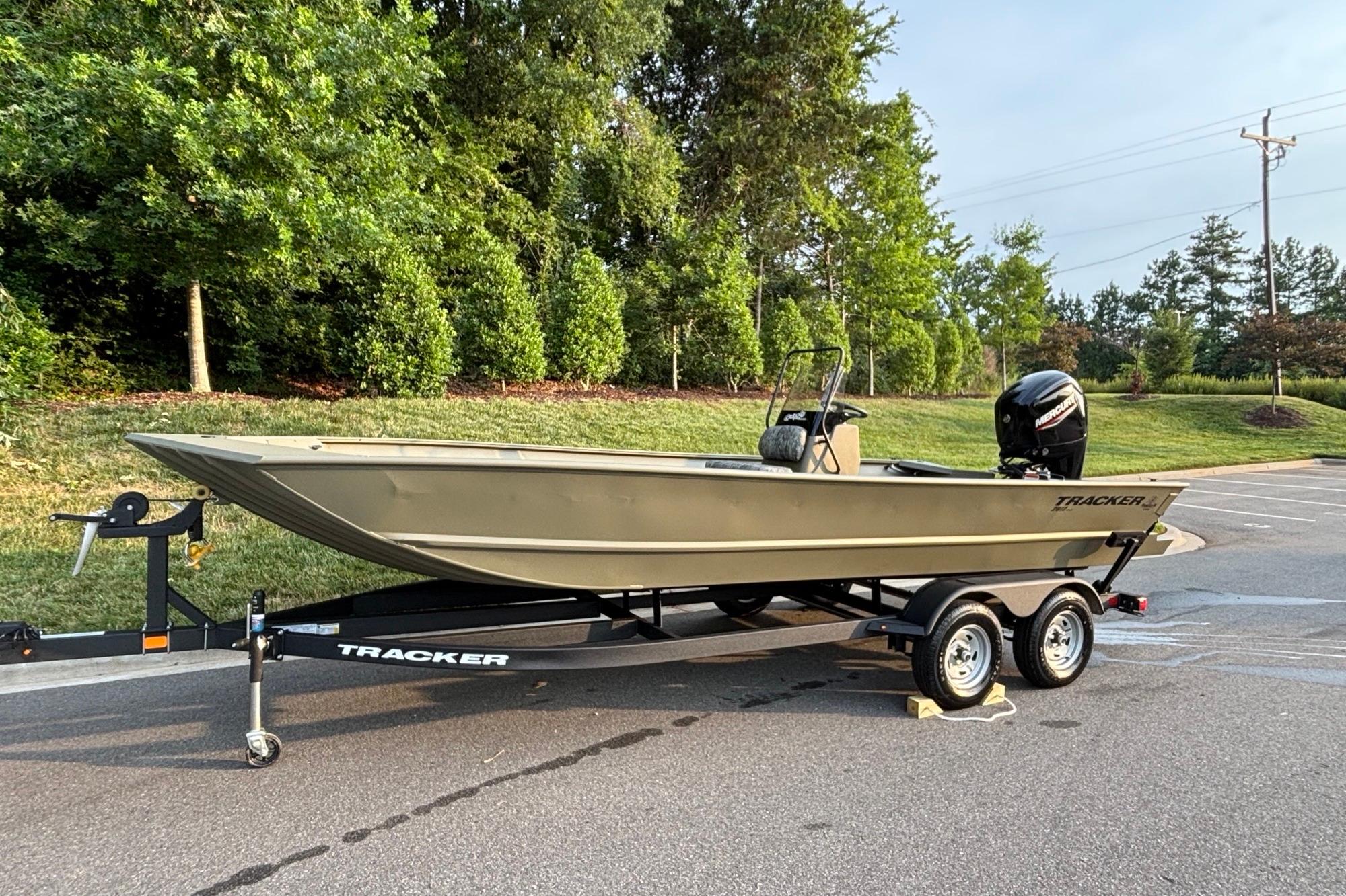 2026 Tracker Grizzly 2072 CC boat on trailer, parked outdoors near greenery.
