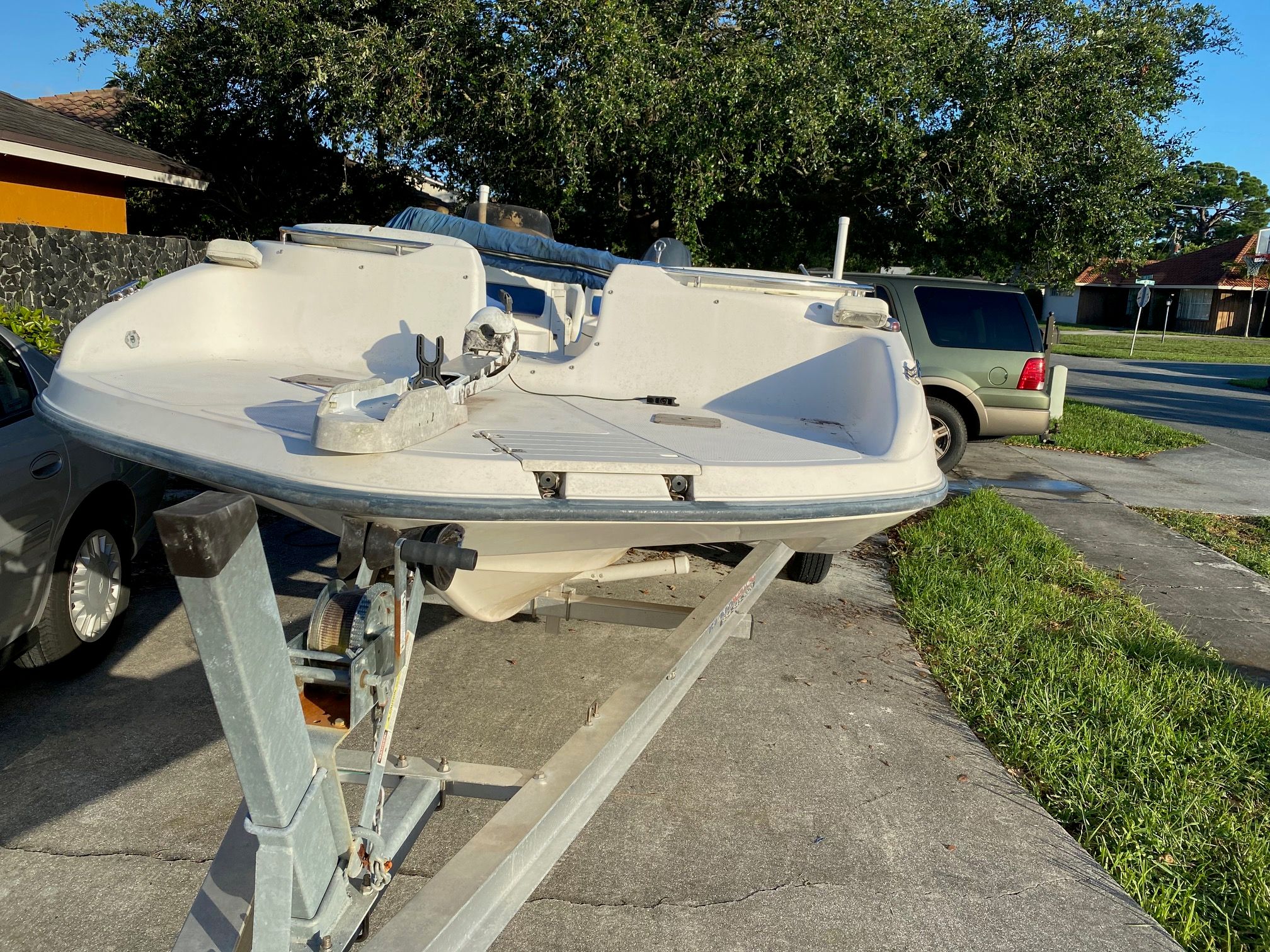 A 2002 Key West Oasis boat is on a trailer in a driveway.