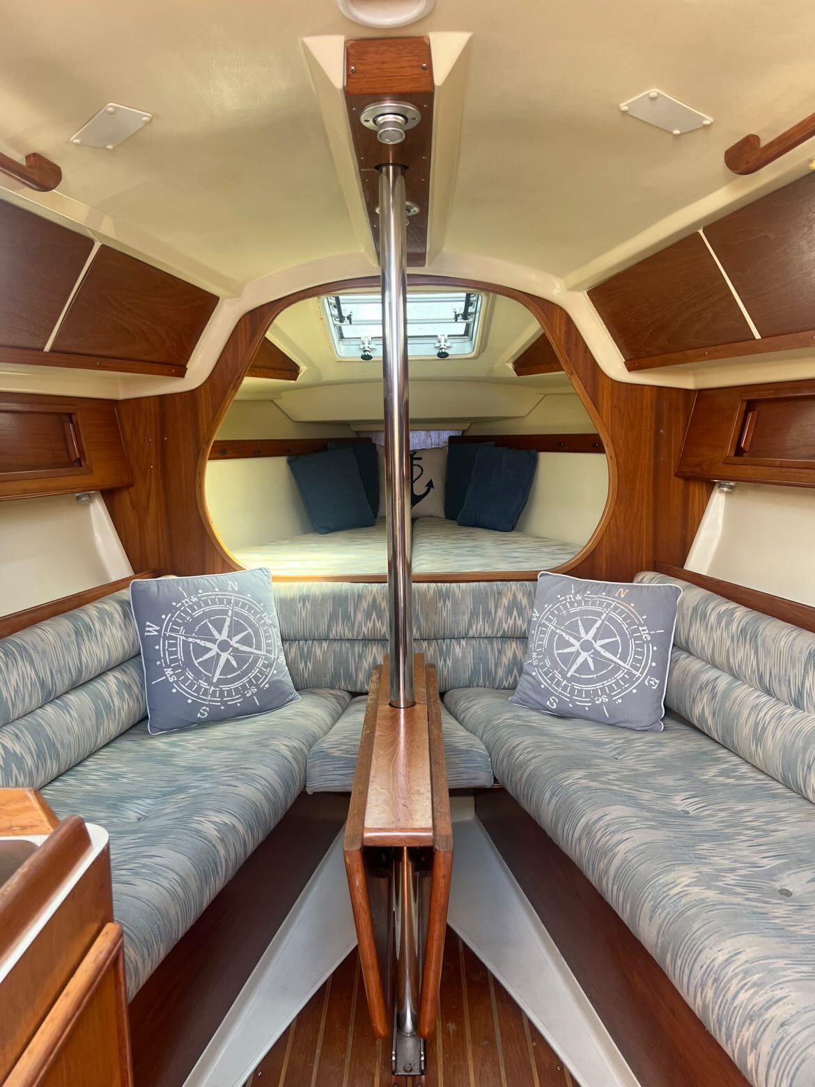 Interior of a 1988 Pearson 28 sailboat with cozy seating and nautical-themed pillows.