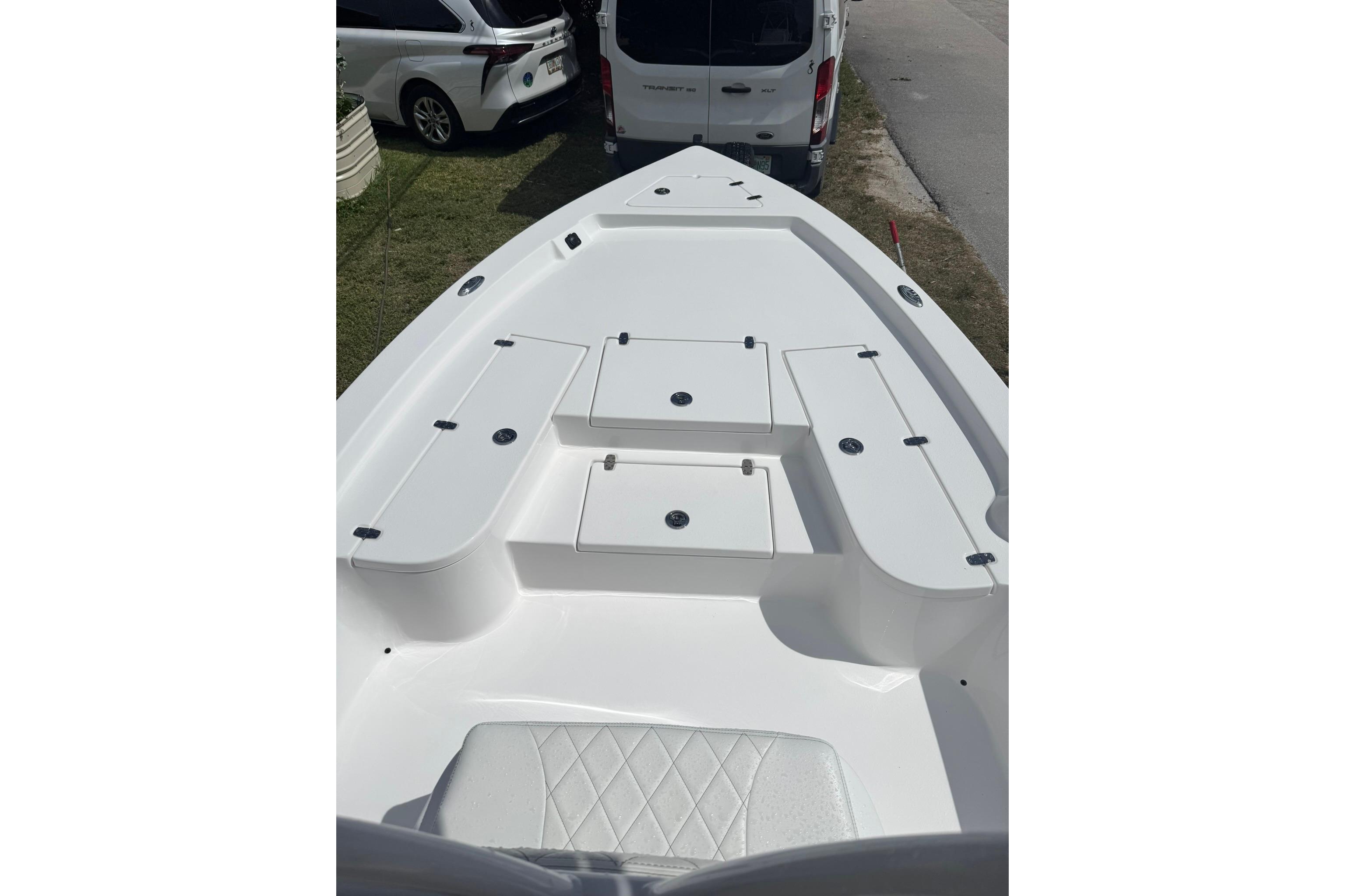 2024 Blazer Bay 2220 Fisherman boat deck with storage compartments, parked near vehicles.