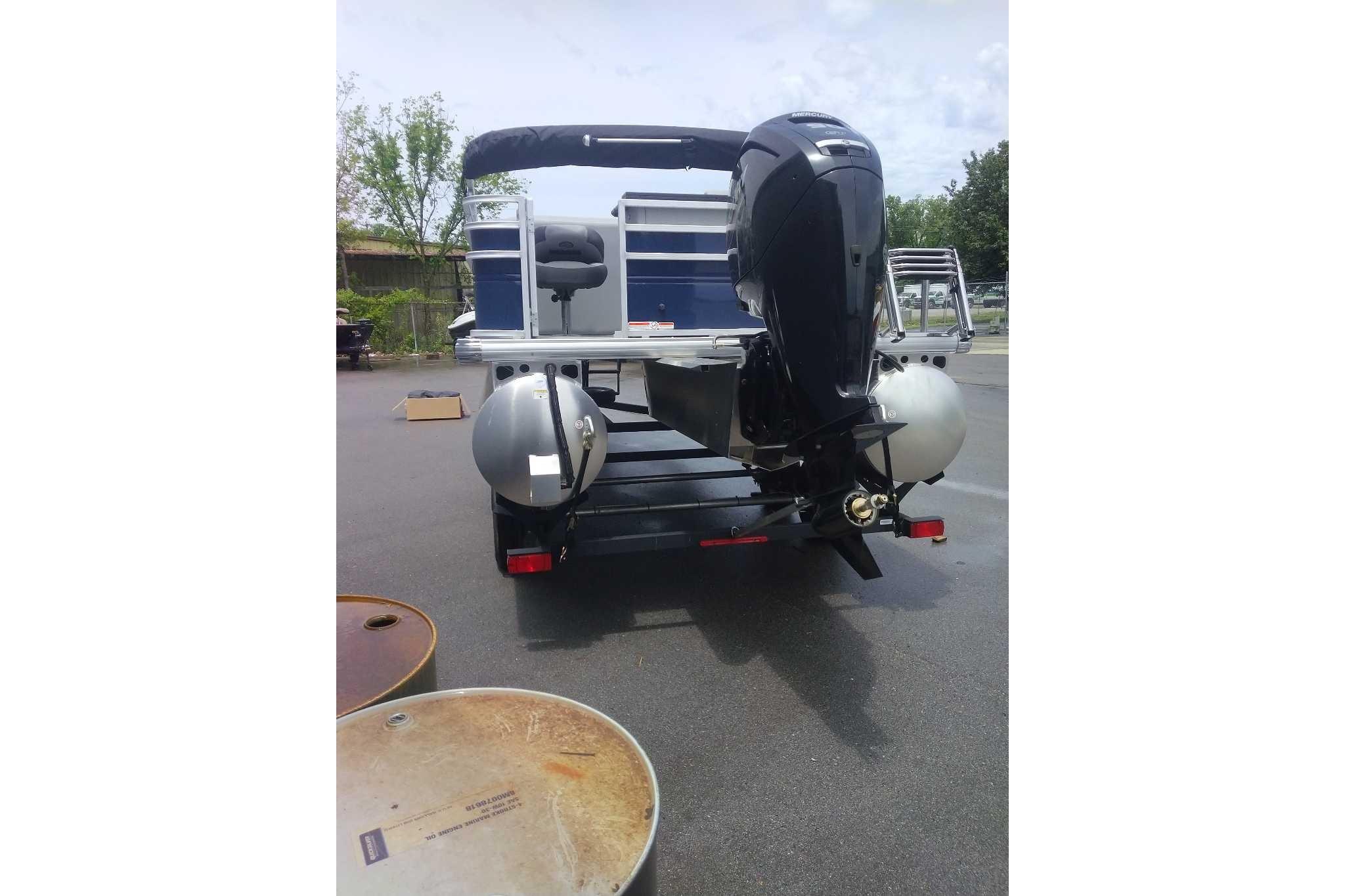 2026 Sun Tracker SportFish 20 DLX pontoon boat with powerful outboard motor, parked outdoors.