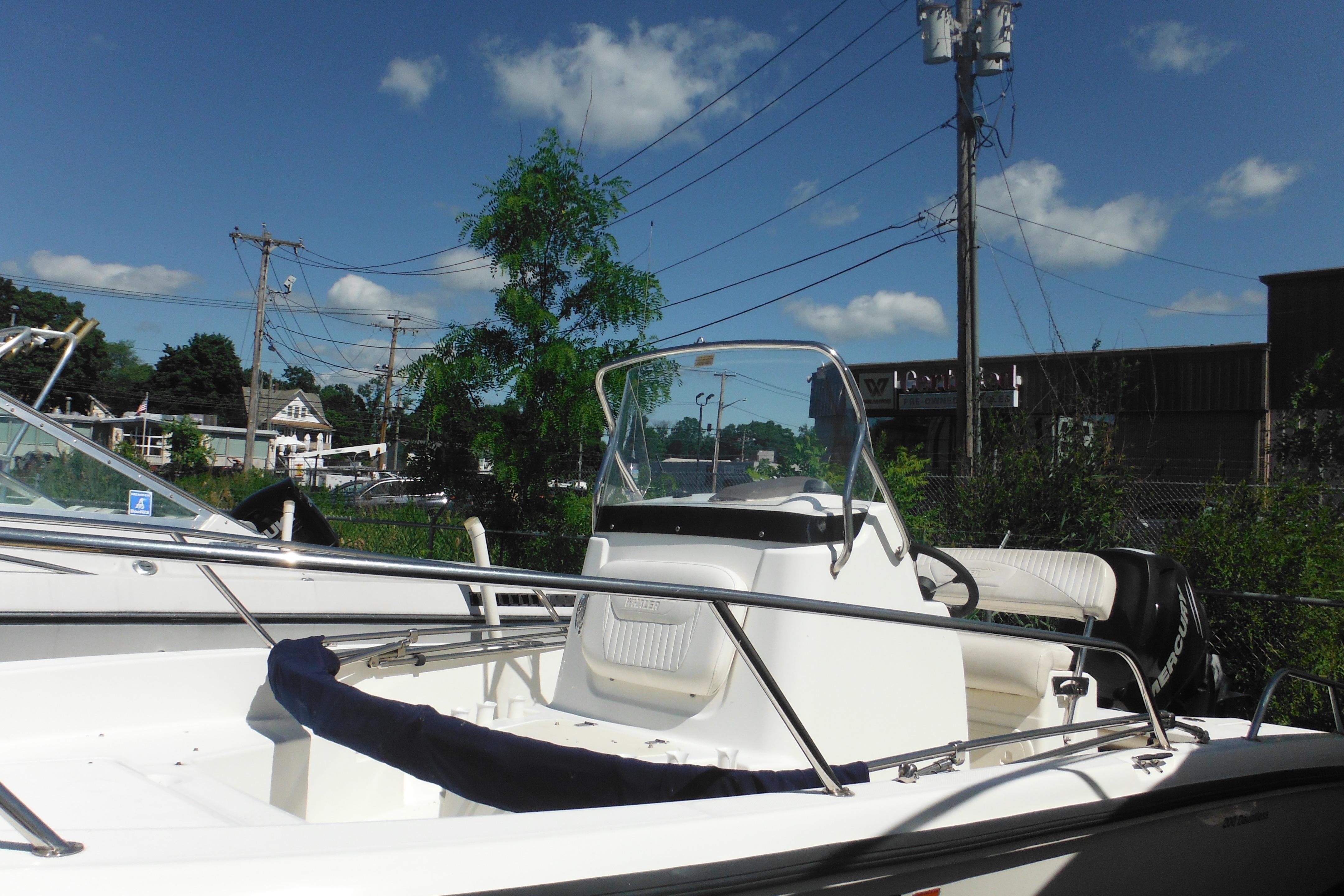 2009 Boston Whaler 200 Dauntless boat with clear skies and lush greenery background.