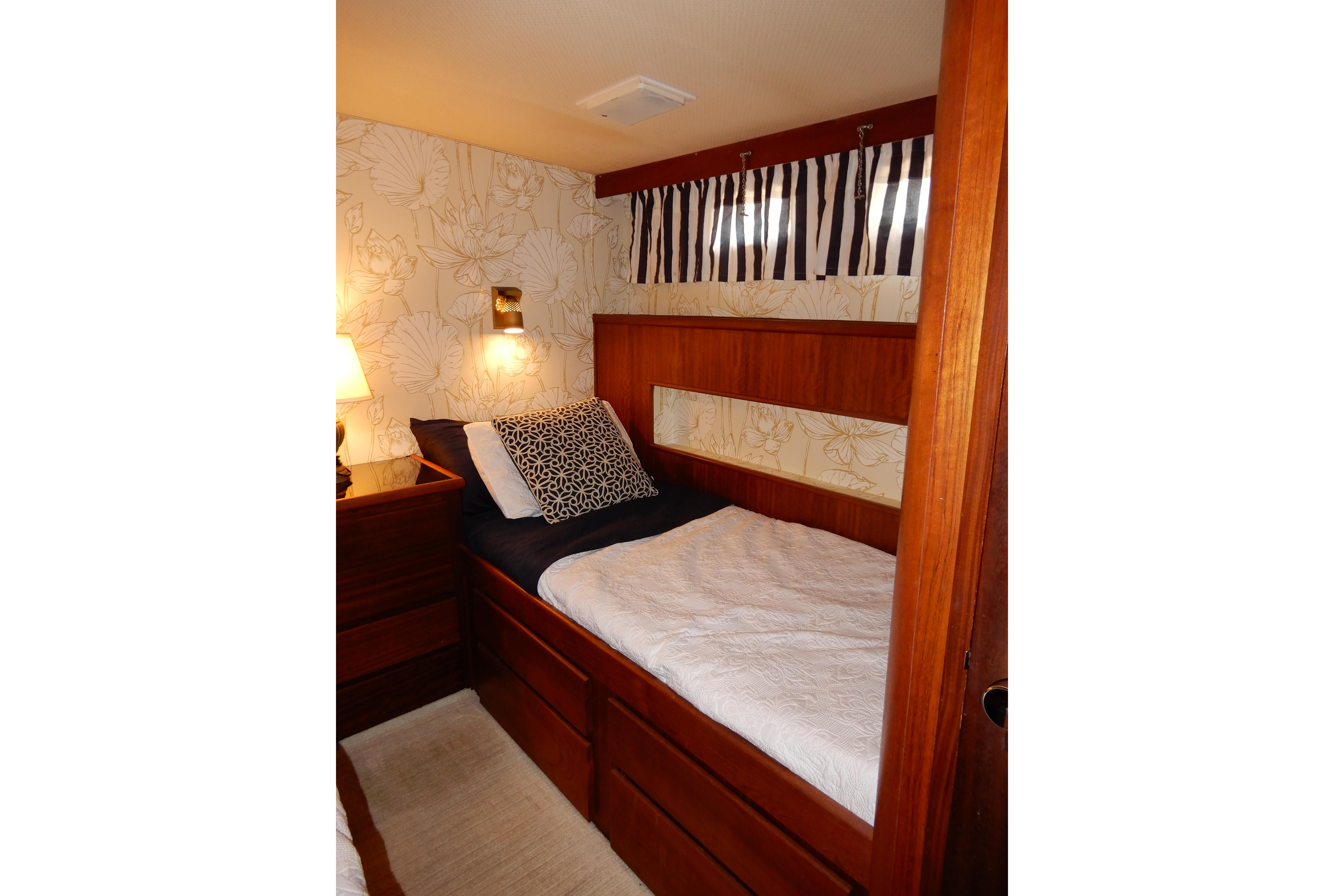 1974 Hatteras 53 Motor Yacht cabin with cozy bed, floral wallpaper, and warm lighting.