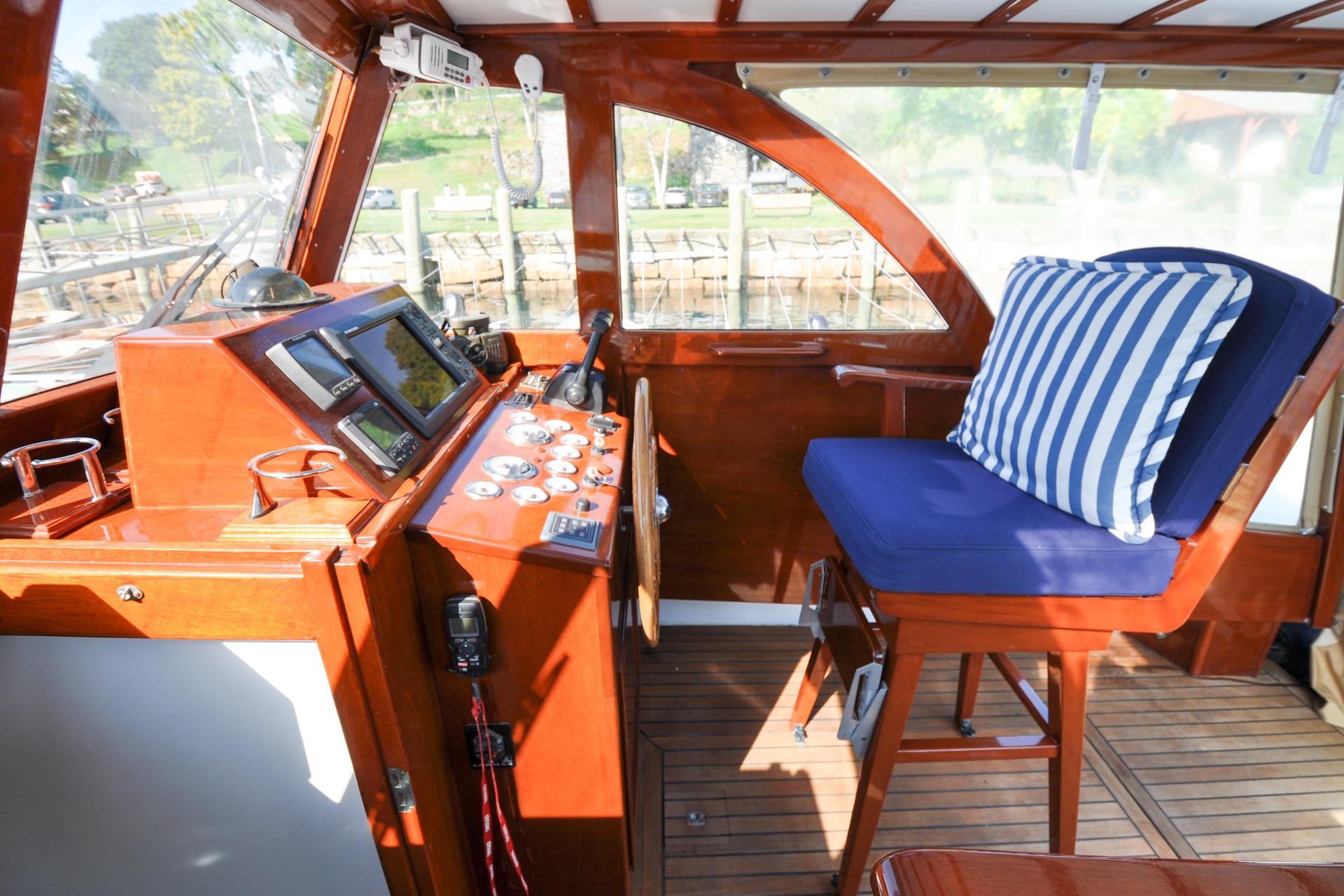 1958 Bunker and Ellis 42 boat interior with wooden helm and striped cushion.