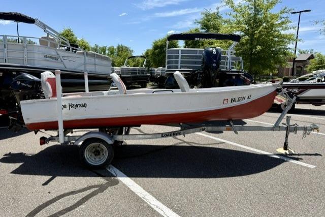 1958 Jon Boat Aluminum on trailer in parking lot, surrounded by trees and other boats.
